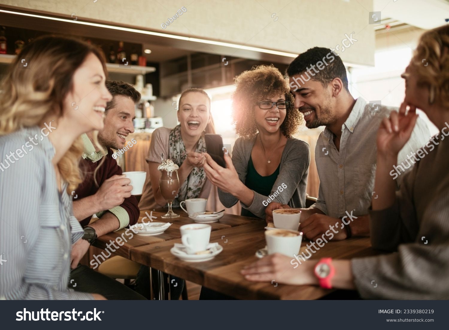 Diverse group of young people talking and having a coffee at a cafe #2339380219