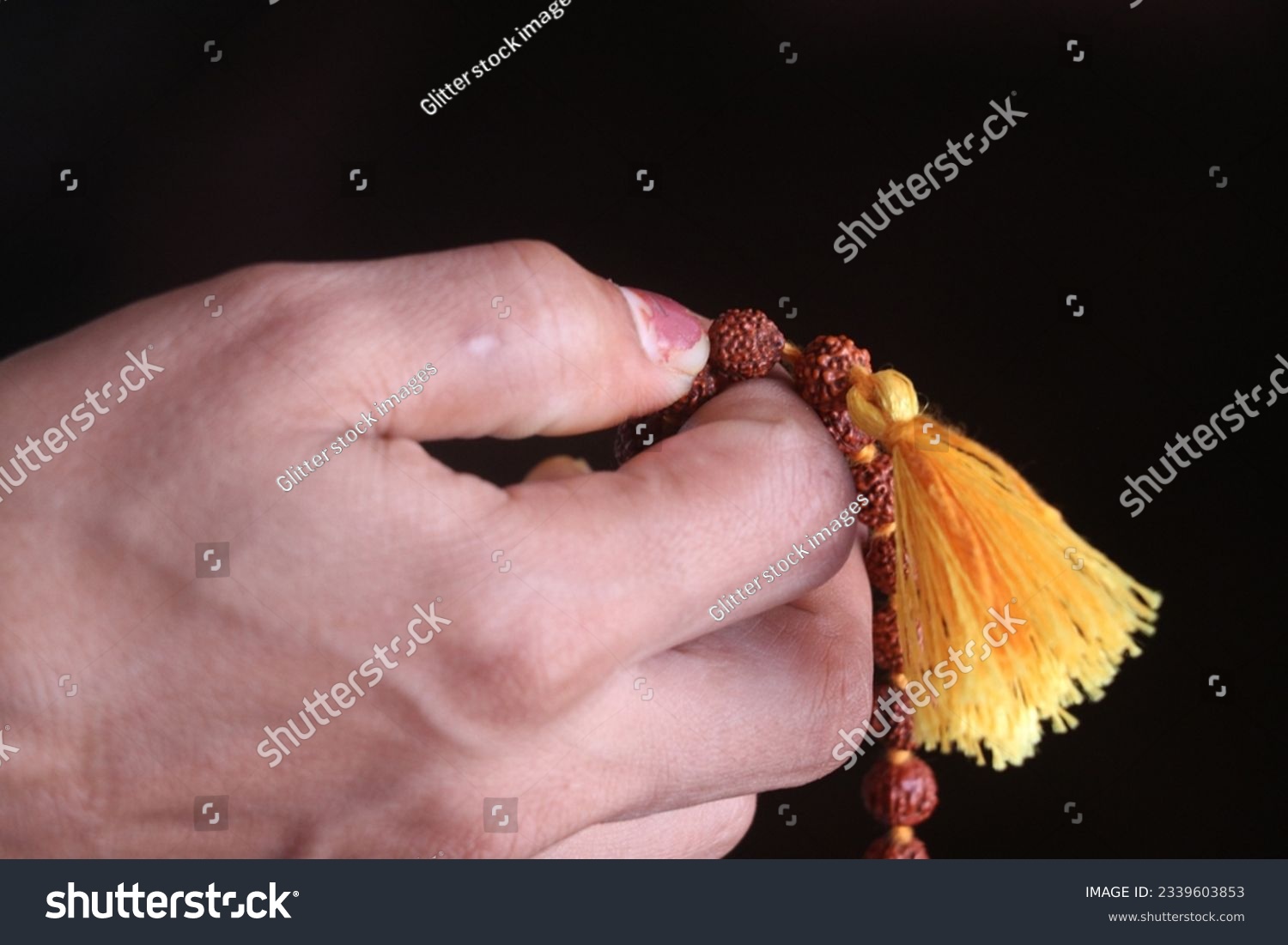 Buddhist prayer beads in a woman's hand on a dark background #2339603853