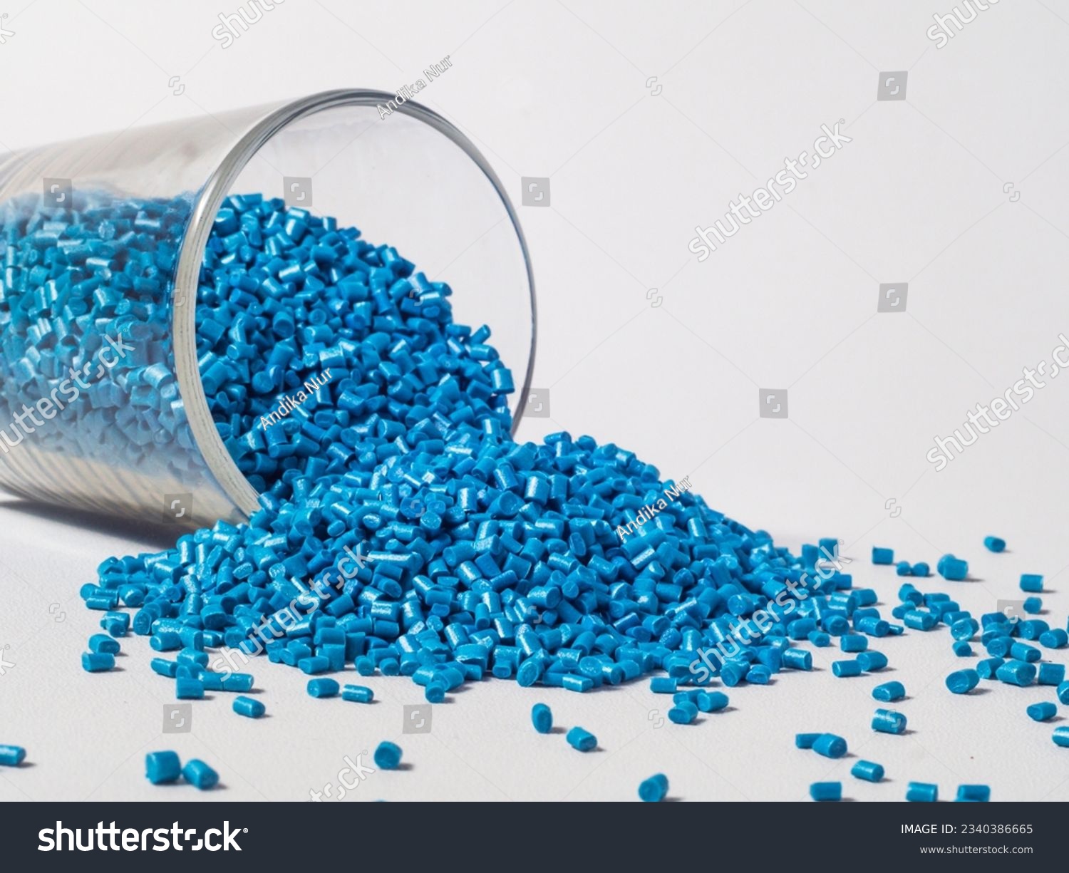 cold cut type blue pearlish masterbatch granules with glass cup in white background photo. This material is a coloring agent for products of the plastics industry #2340386665