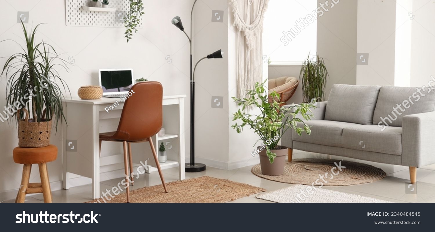 Interior of light living room with grey sofa, modern workplace and houseplants #2340484545