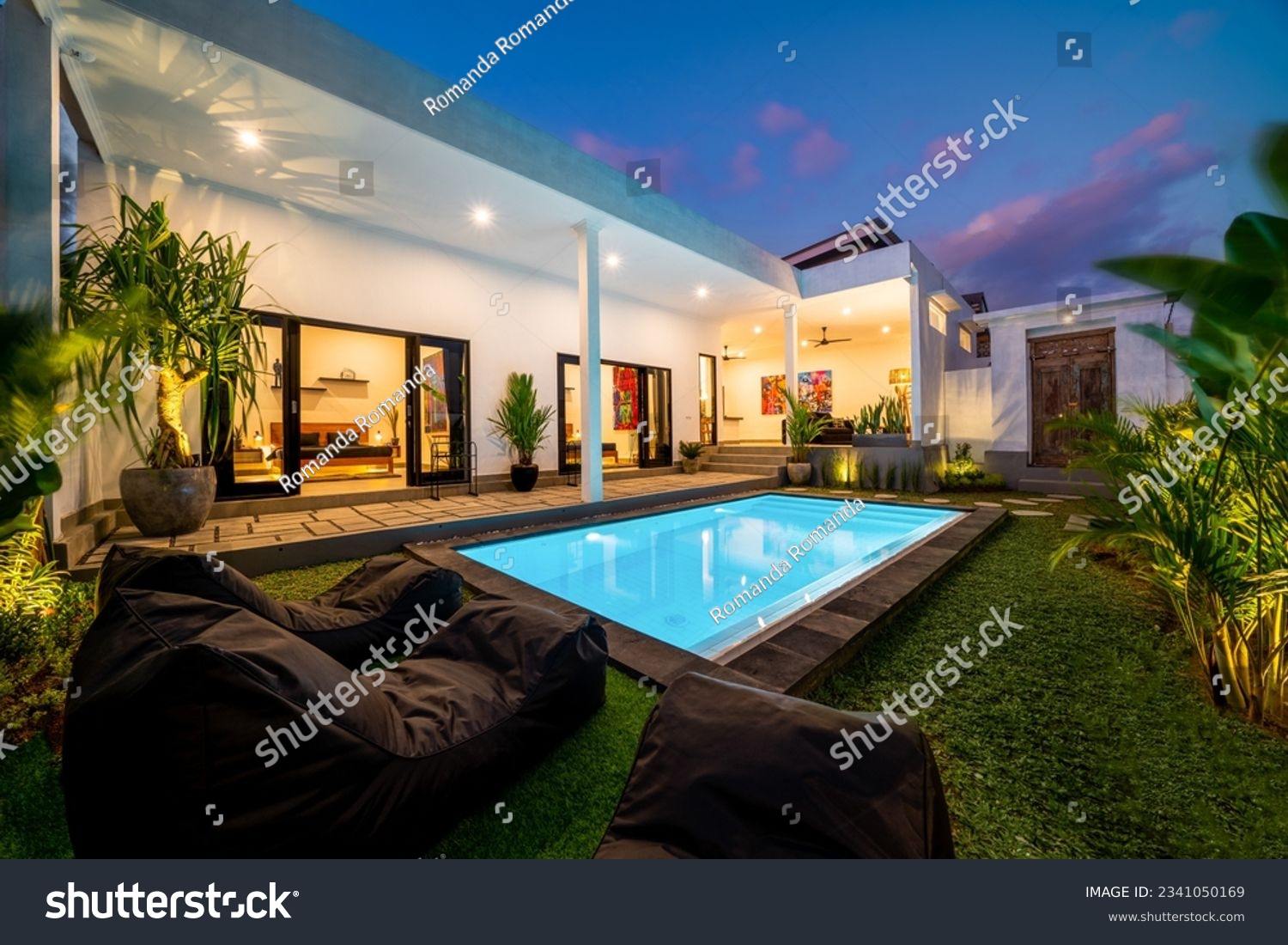 Tropical villa view with garden, swimming pool and open living room at sunset. #2341050169