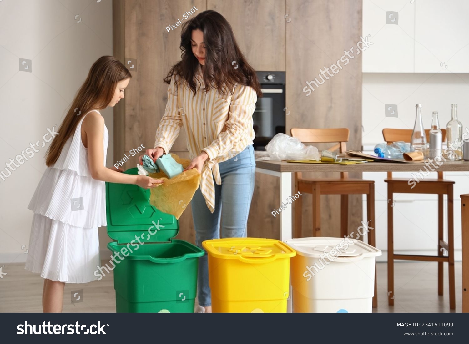 Little girl with her mother sorting paper garbage in kitchen #2341611099