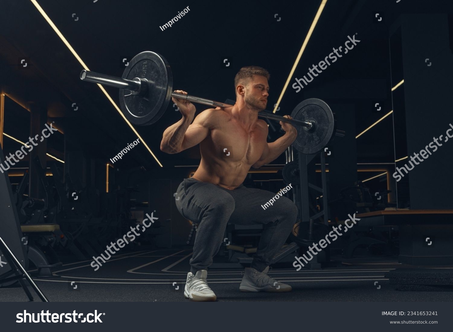 Muscular man doing squats with barbell in a gym. Male bodybuilder doing workout Confident young man doing barbell workout in gym Powerful attractive man. #2341653241