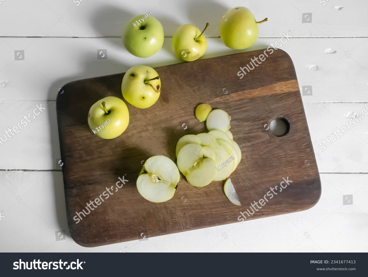 Processing of wormy apples. Spoiled apples with black dots - crop processing. Slicing an apple on a wooden board. #2341677413