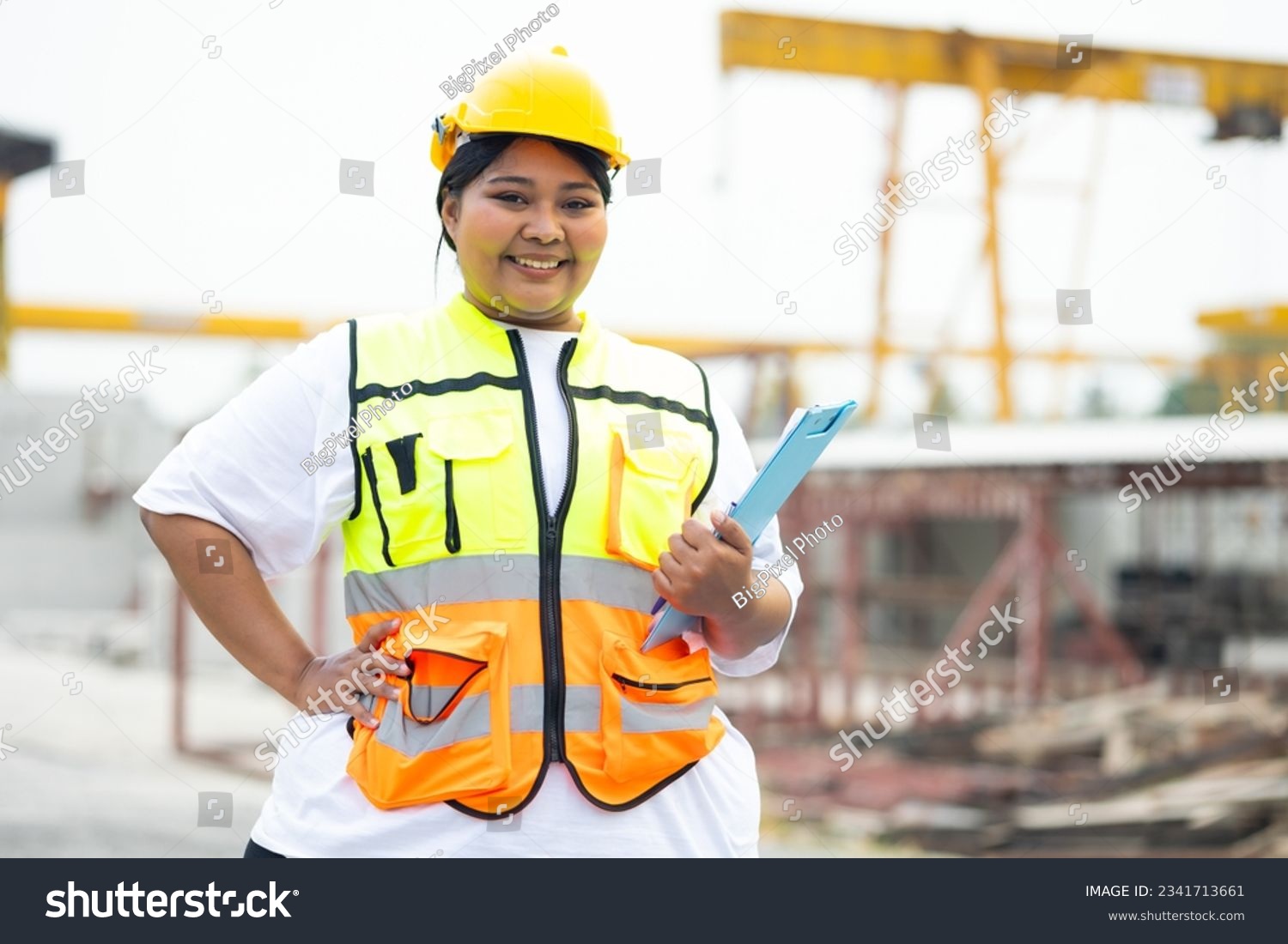 Plus size female factory worker wearing safety hard hat helmet working at heavy Prefabricated concrete walls manufacturing factory. Portrait African american woman #2341713661