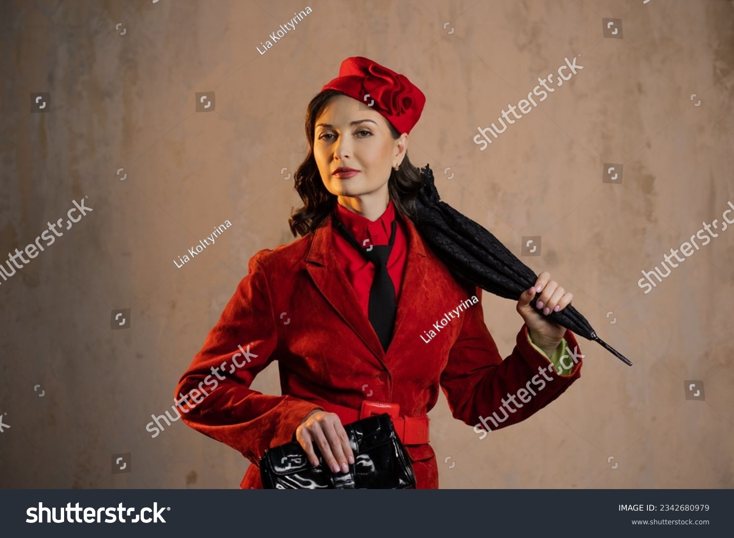 A stylish lady in a red old-fashioned suit with a hat and a lace umbrella #2342680979