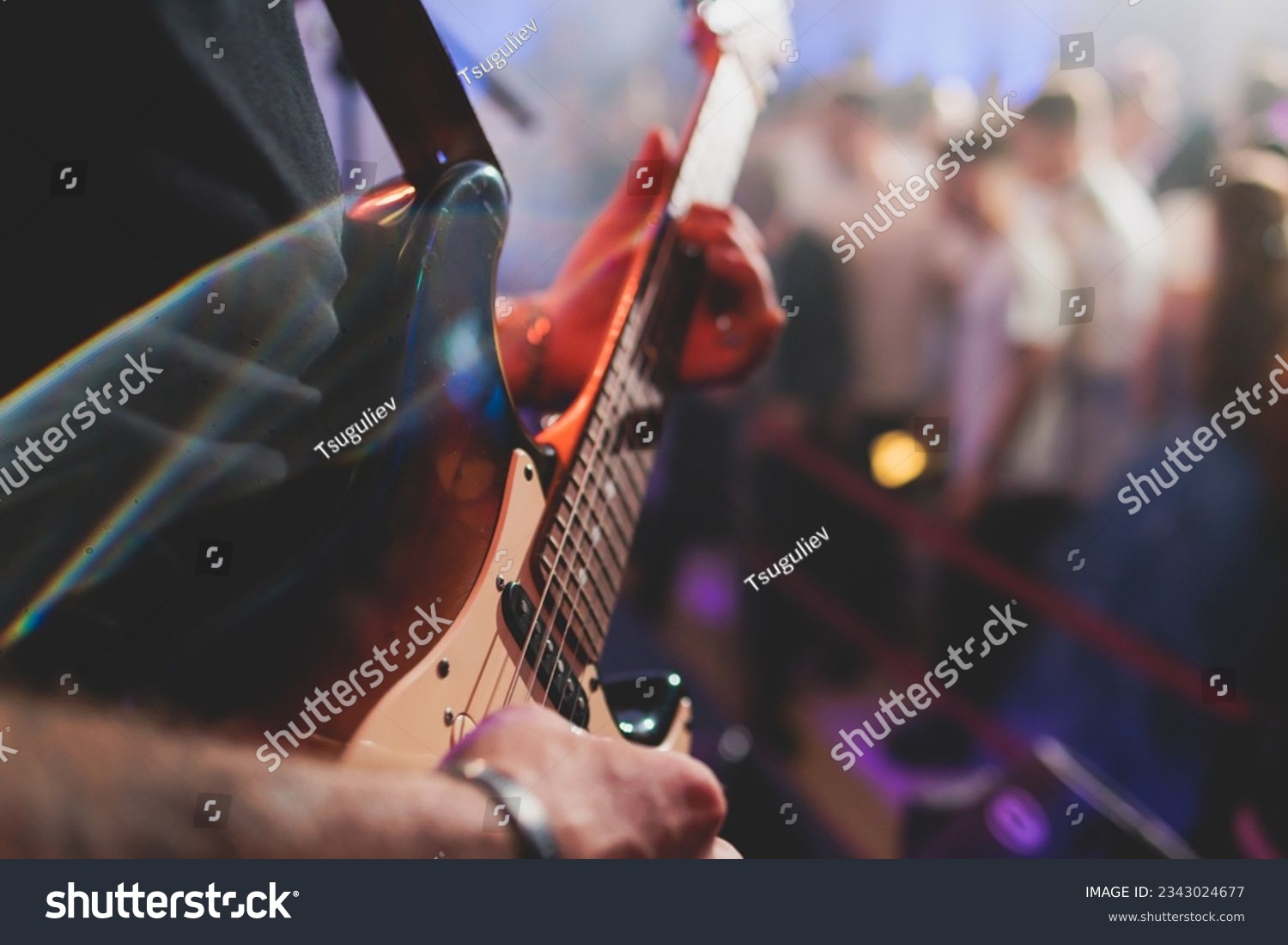 Concert view of an electric guitar player with vocalist and rock band performing in a club, male musician guitarist on stage with audience in a crowded concert hall arena
 #2343024677