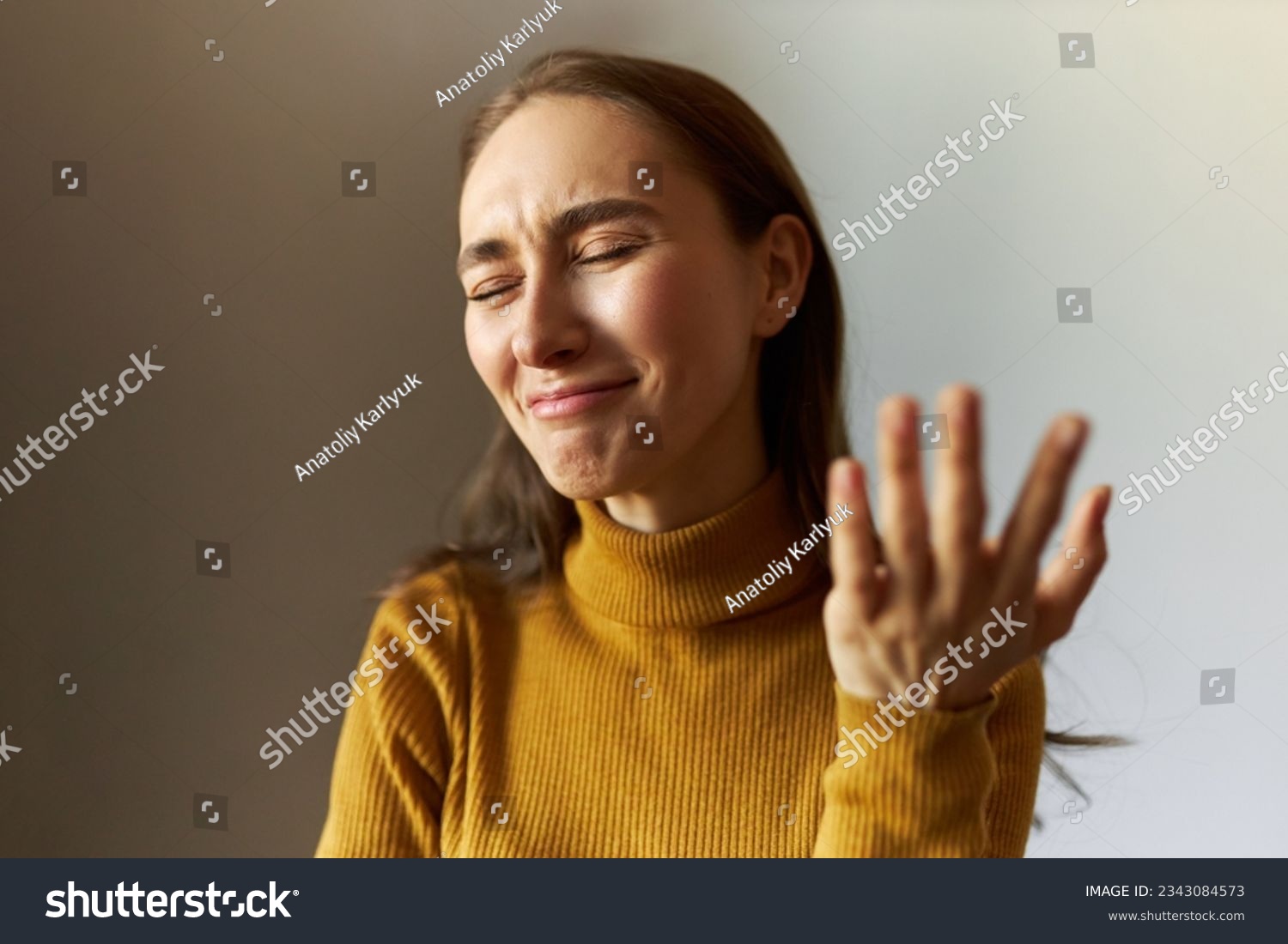 Emotional caucasian young girl standing against gray background with closed eyes and failed facial expression, feeling ashamed and laughing with desperation, gesticulating with regret #2343084573