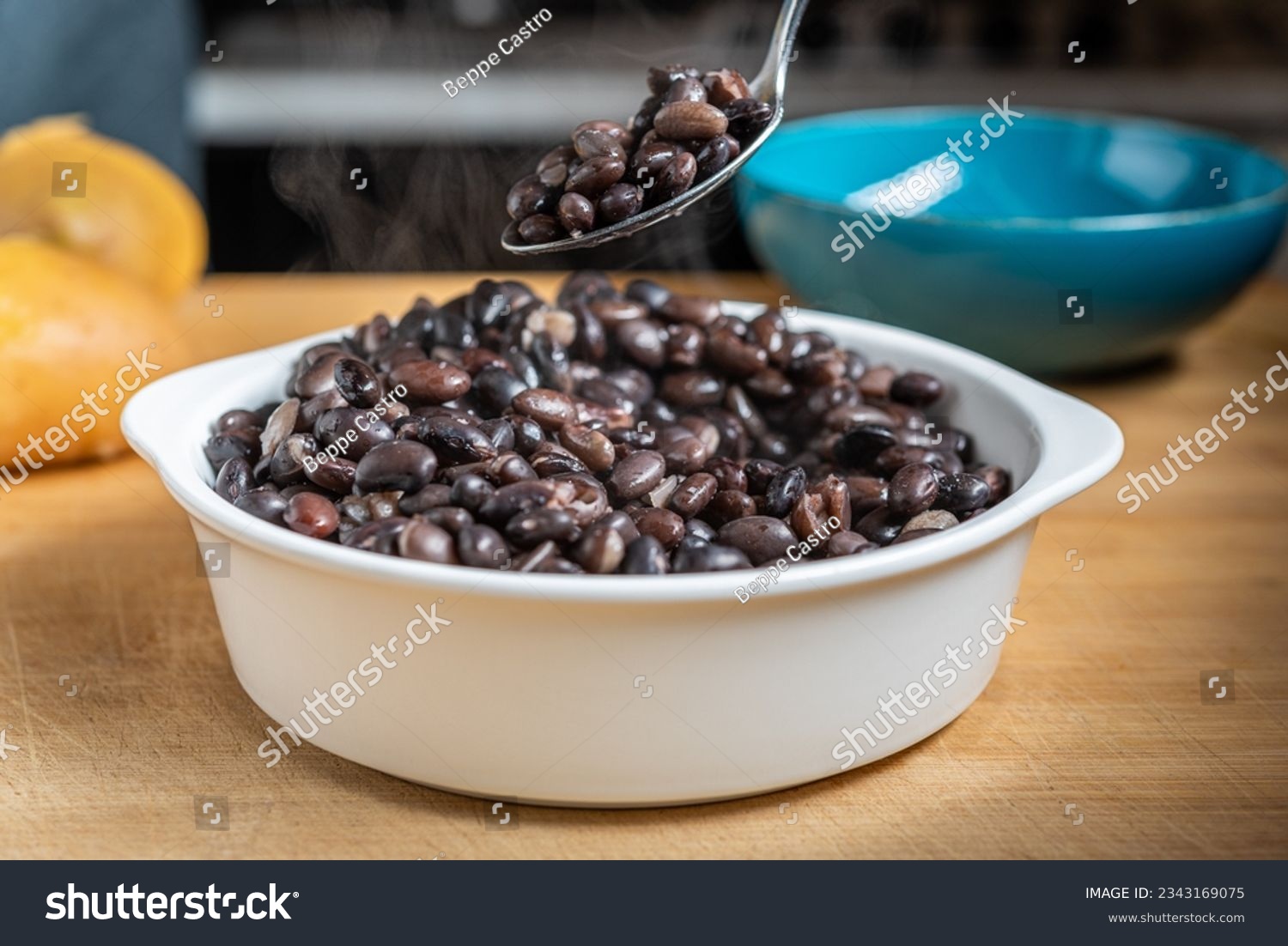 Cooked black beans in a white bowl on a wooden table being mixed #2343169075