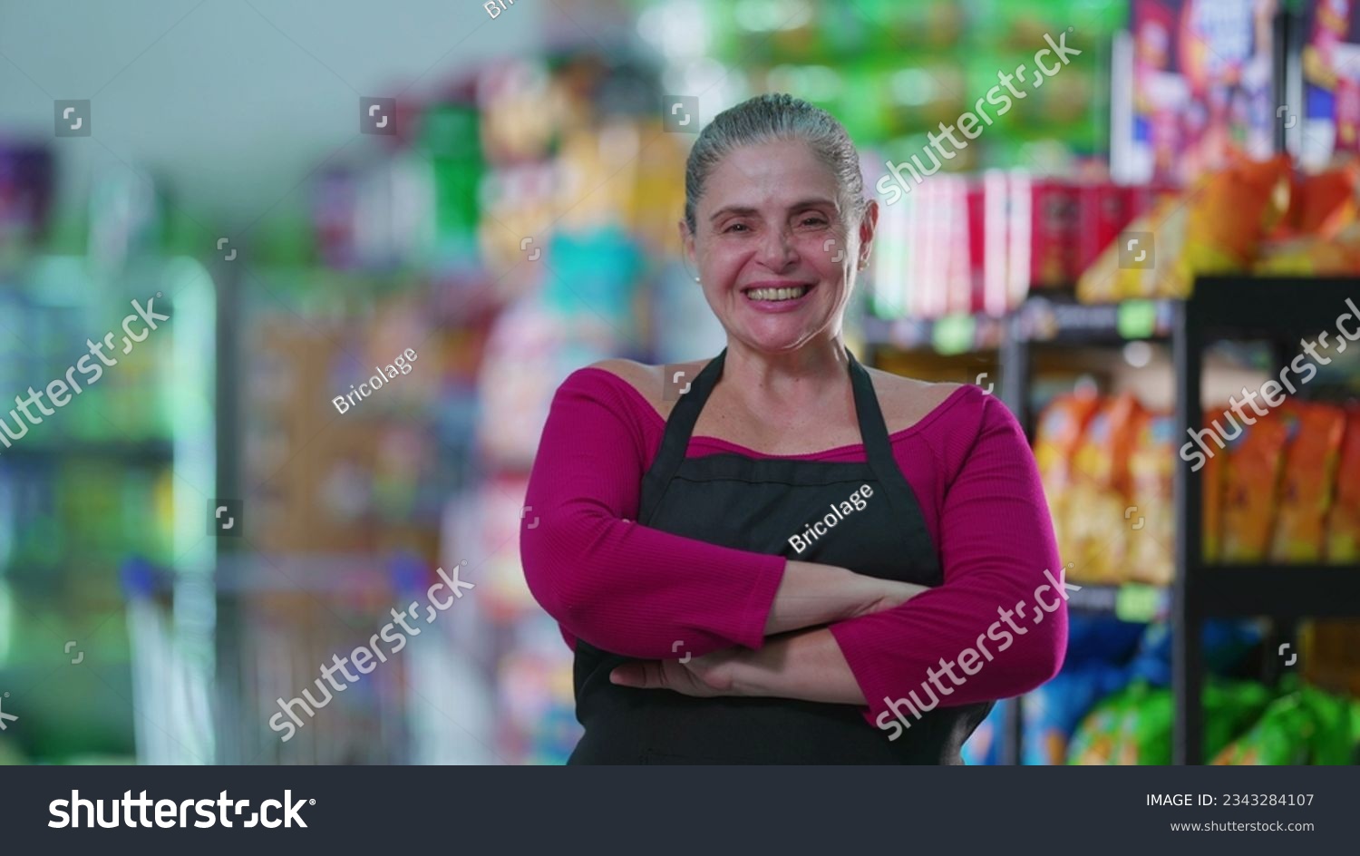 Joyful Female Grocery Store Worker Smiling at Camera with arms crossed, Wearing Apron #2343284107