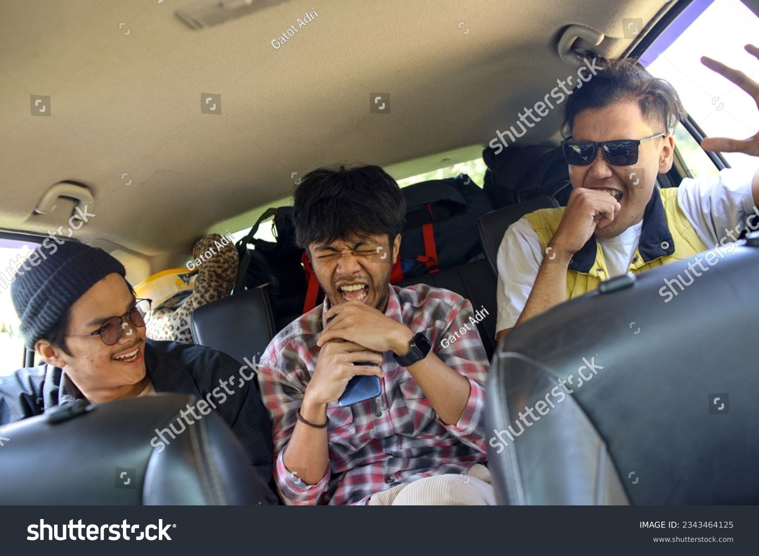 Three best male friends travel together. Sitting in a backseat car and having fun singing to a song. Summer adventure concept. #2343464125