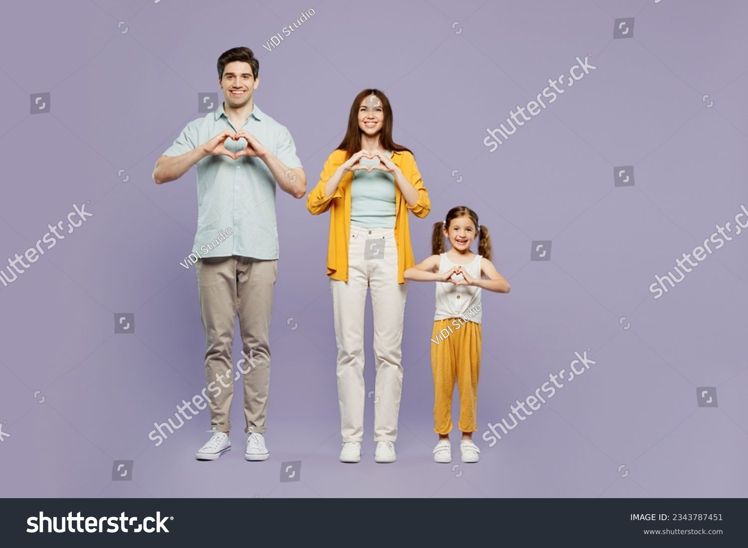 Full body young parents mom dad with child kid daughter girl 6 years old wear yellow casual clothes show shape heart with hands heart-shape sign isolated on plain purple background. Family day concept #2343787451