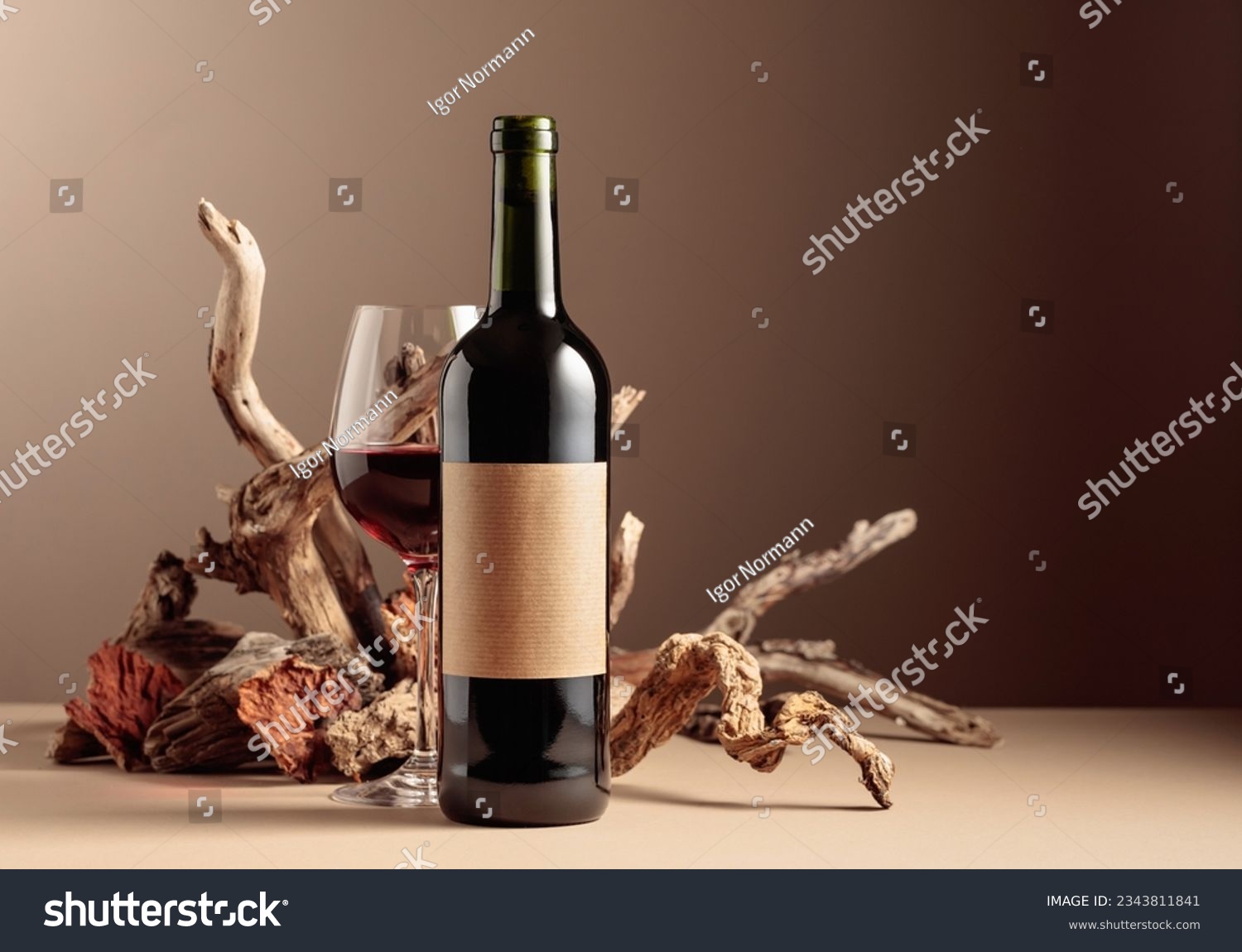 Bottle and glass of red wine with a composition of old wood. Minimalistic composition on a beige background for product branding, identity, and packaging. Copy space. #2343811841