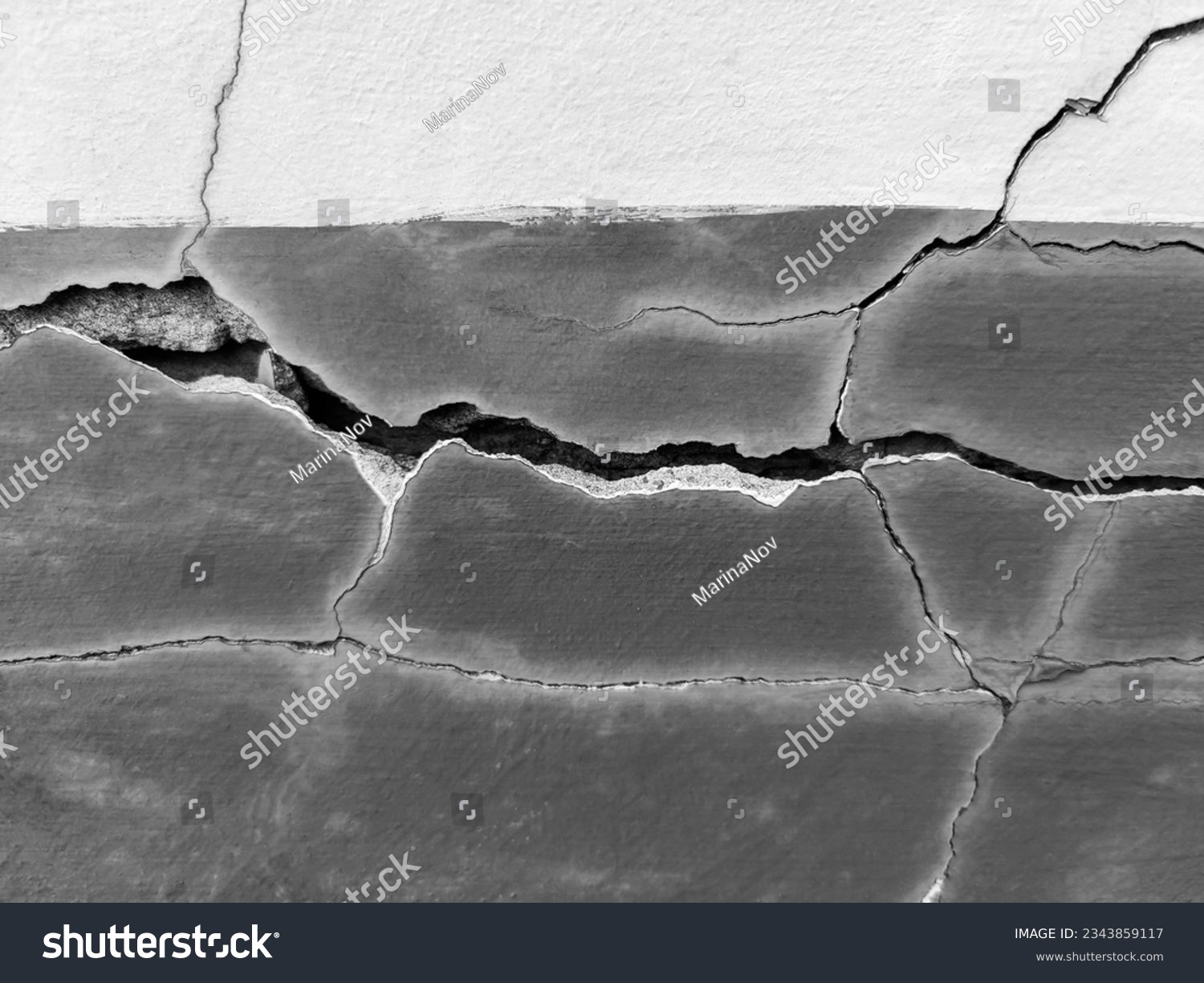 Big long tortuous crack on the wall. Destructions on the wall of an old building. Copy space. Black and white photo. Selective focus. #2343859117