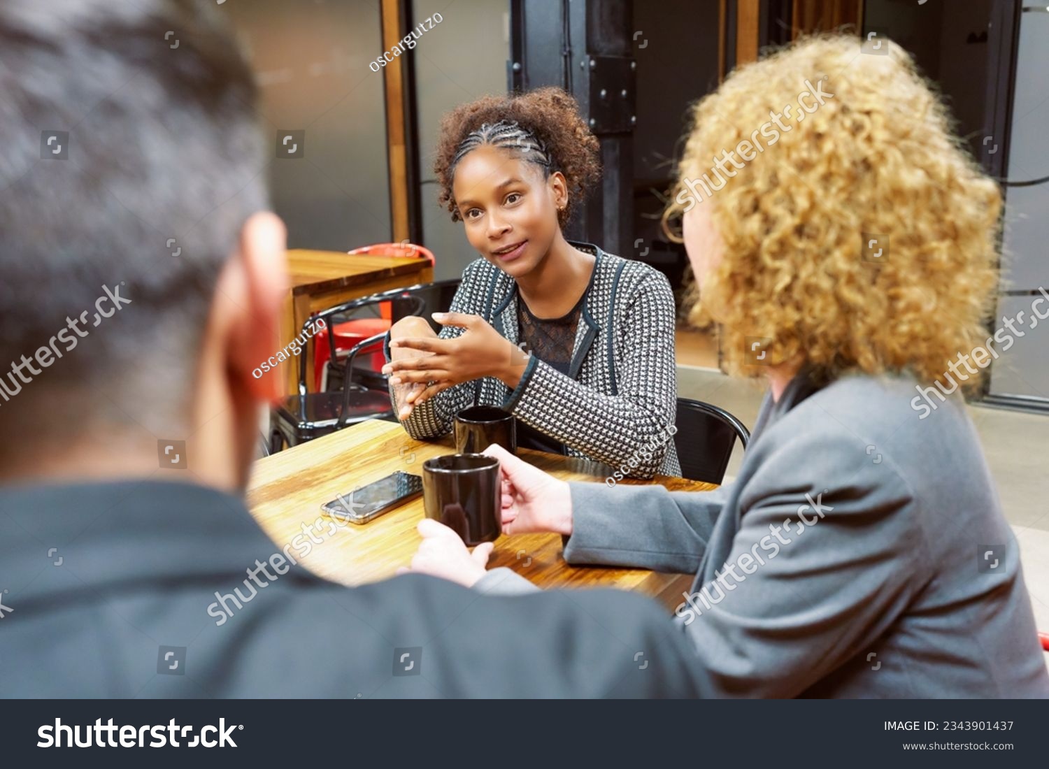 portrait young black woman sitting in meeting with group of business people talking #2343901437