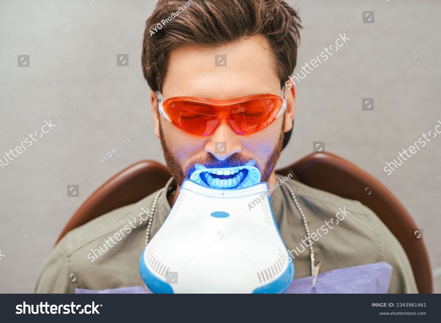 Portrait of handsome bearded middle aged man sitting in dental chair wearing red eyeglasses with open mouth, teeth whitening. Male patient in modern clean dentistry. Concept of dental treatment #2343961461