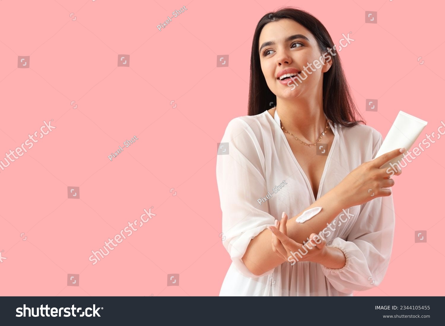 Young woman applying sunscreen cream on pink background #2344105455