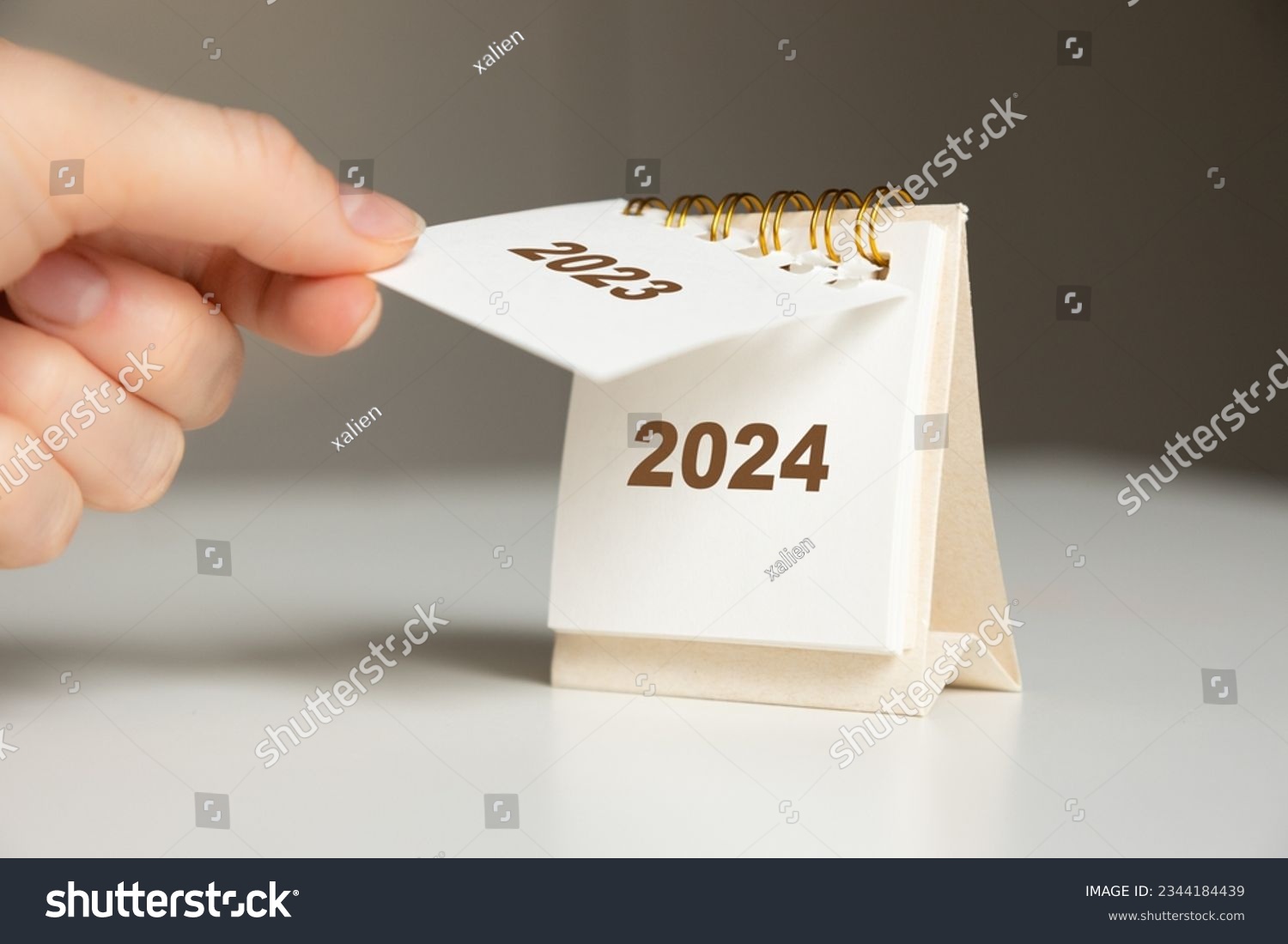 a woman's hand turns over a calendar sheet. year change from 2023 to 2024 #2344184439