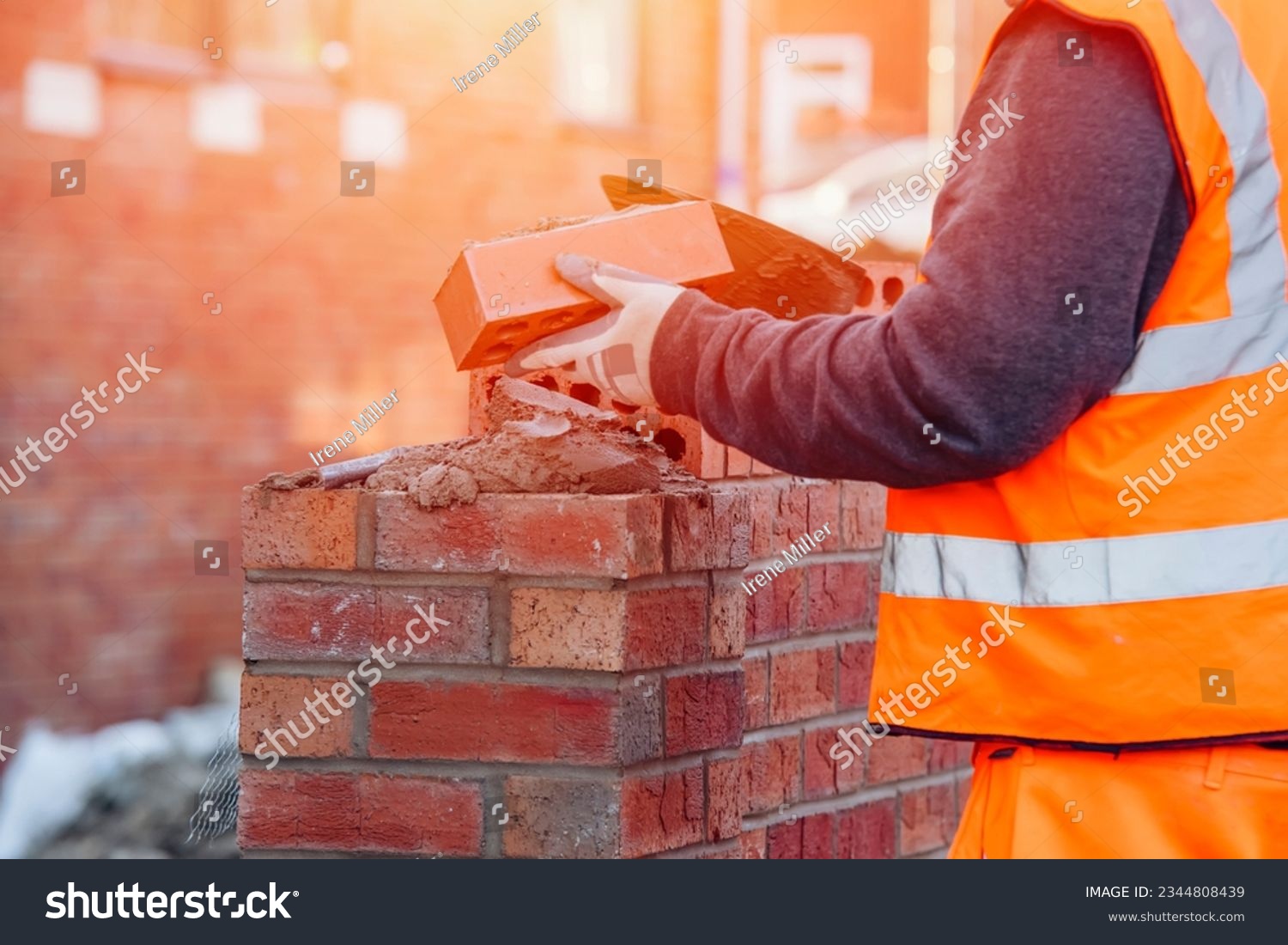 Hard working bricklayer lays bricks on cement mix on construction site. Fight housing crisis by building more affordable houses concept #2344808439