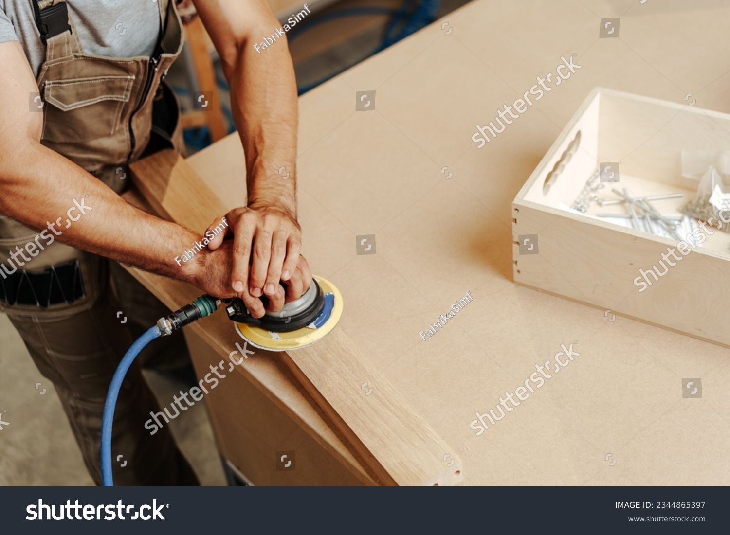Close up of carpenter hands sanding wood with orbital sander at workshop #2344865397