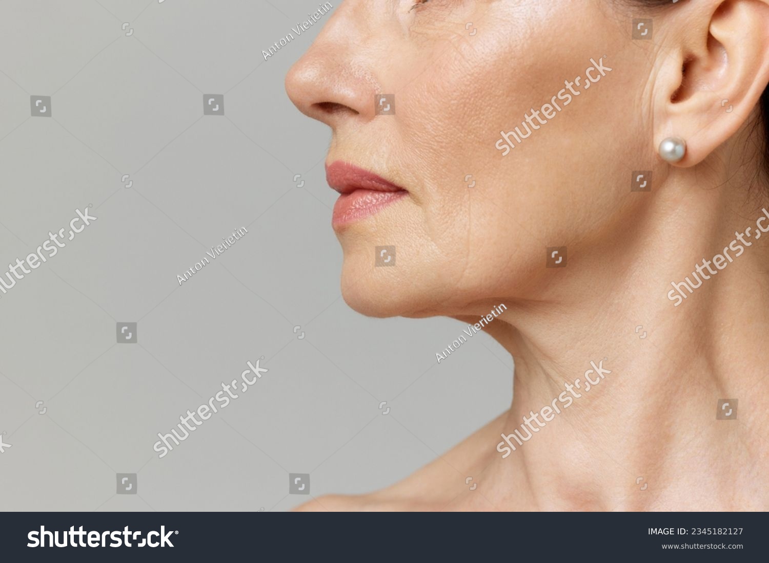 Double chin treatment. Cropped profile portrait with lips and chin neckline of middle-aged woman over grey studio background. Fashion, beauty, spa, cosmetology, skincare concept. #2345182127