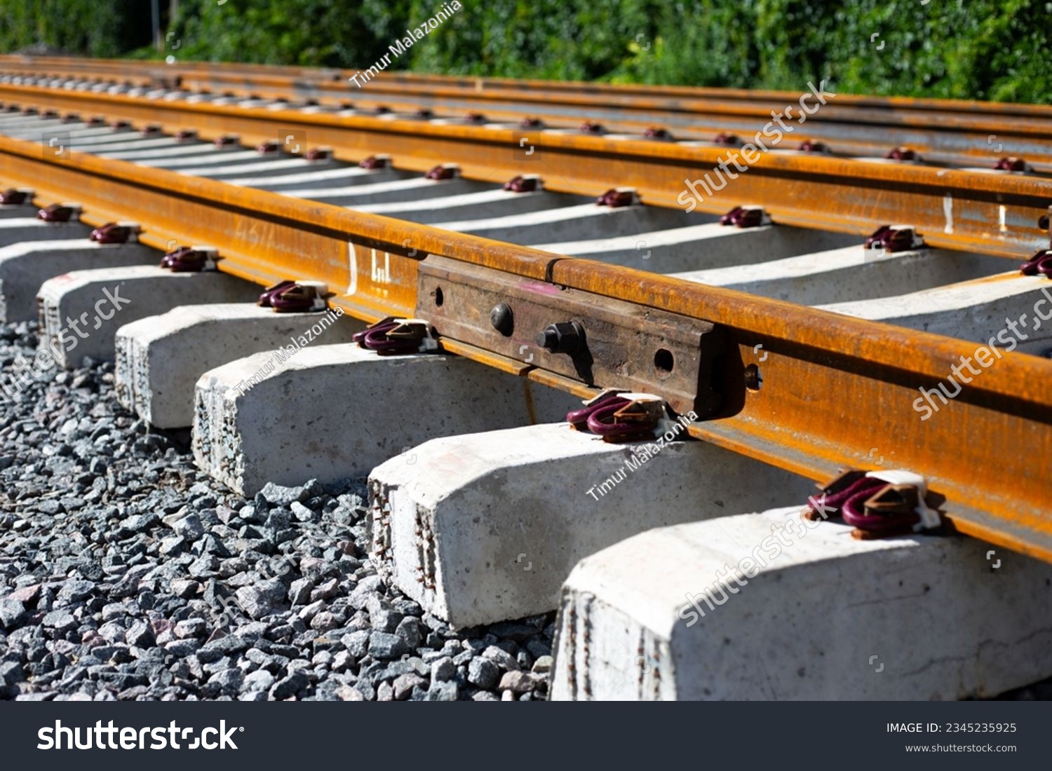 Rusty intermediate rail fasteners on concrete sleepers for train and tram, laying railroad tracks #2345235925
