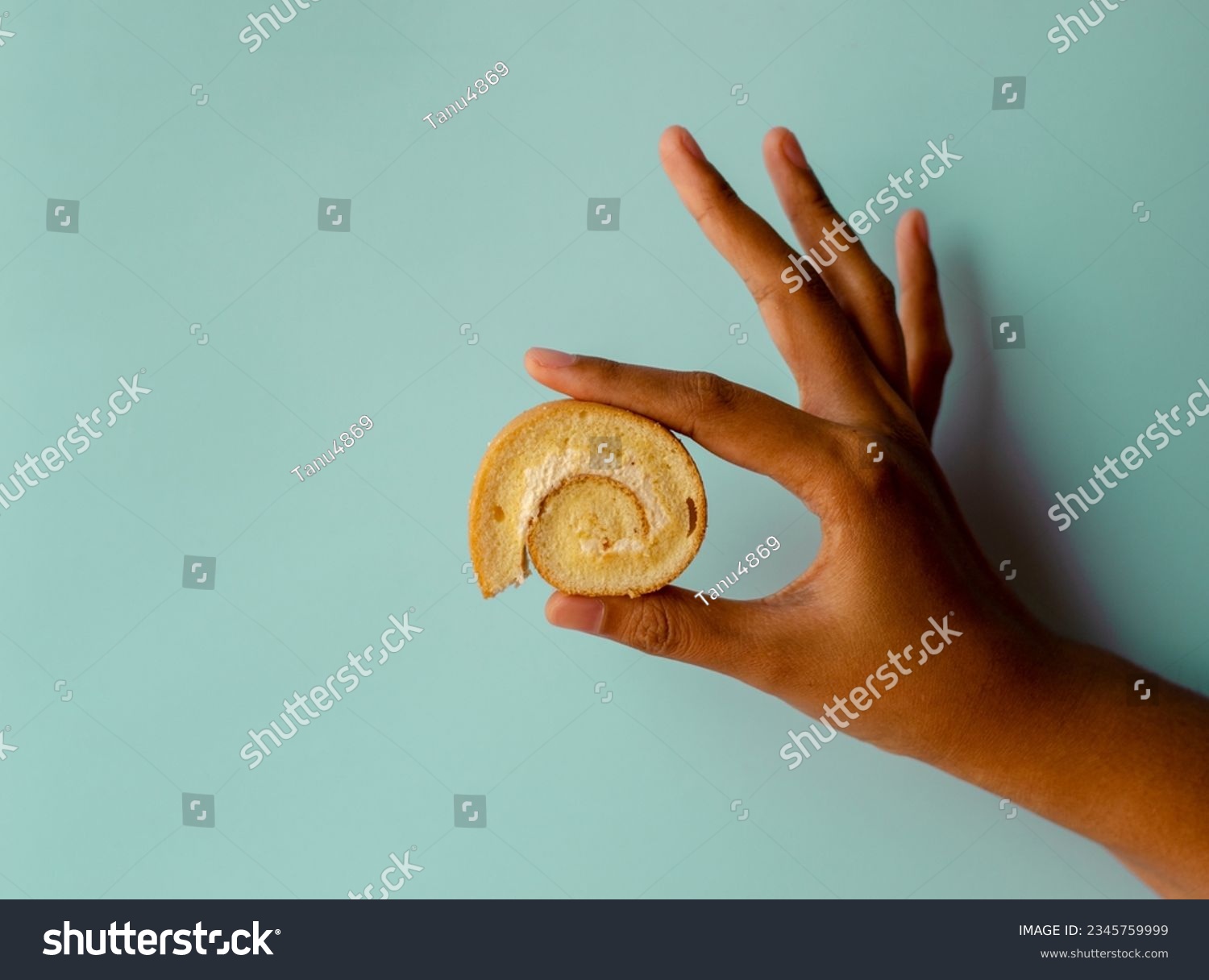 Young asian women holding mini vanilla roll cake, swiss roll cake or sponge roll with Vanilla flavor. Thai call Jam Rolls. isolated on blue background #2345759999