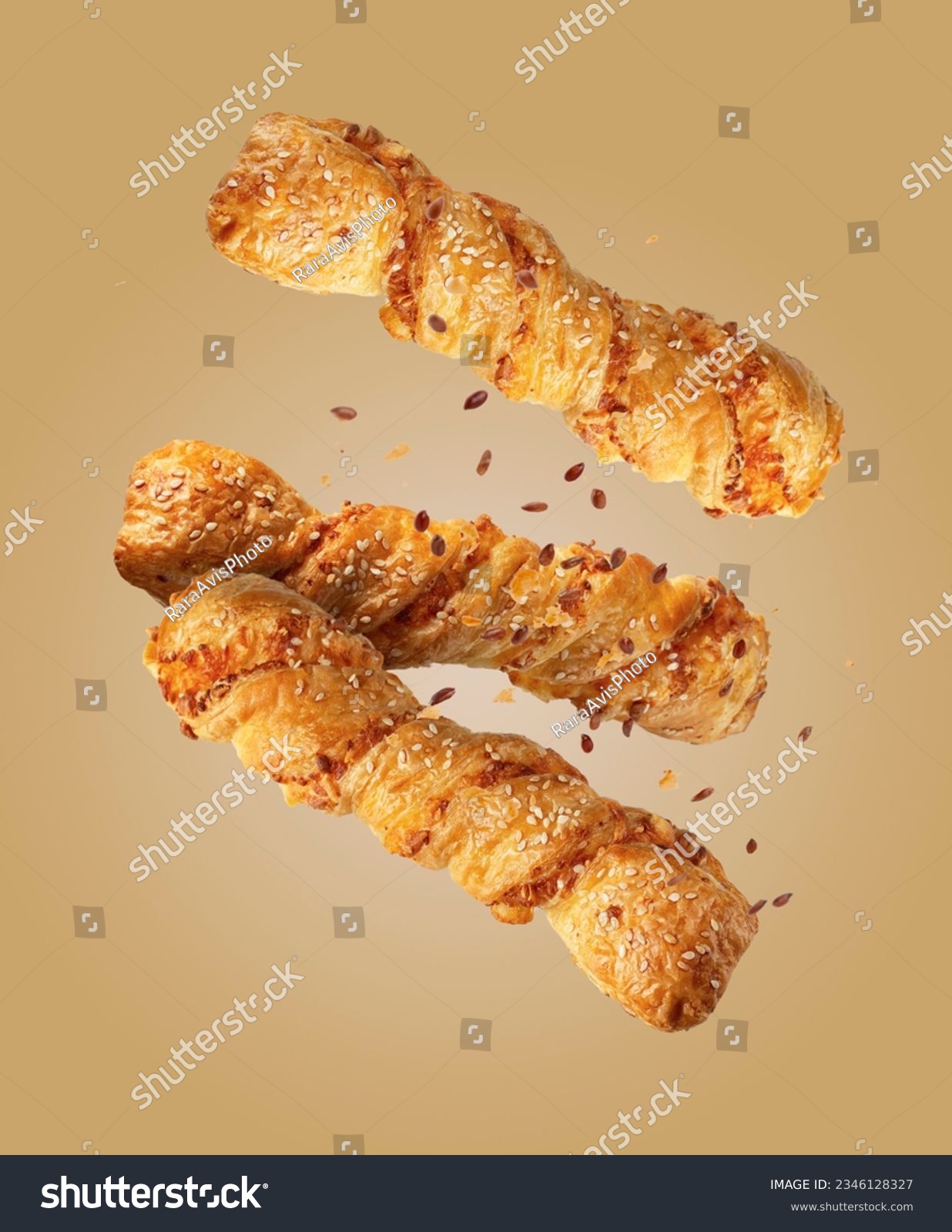 twist puff pastry with sesame seeds on a beige background, flying food #2346128327