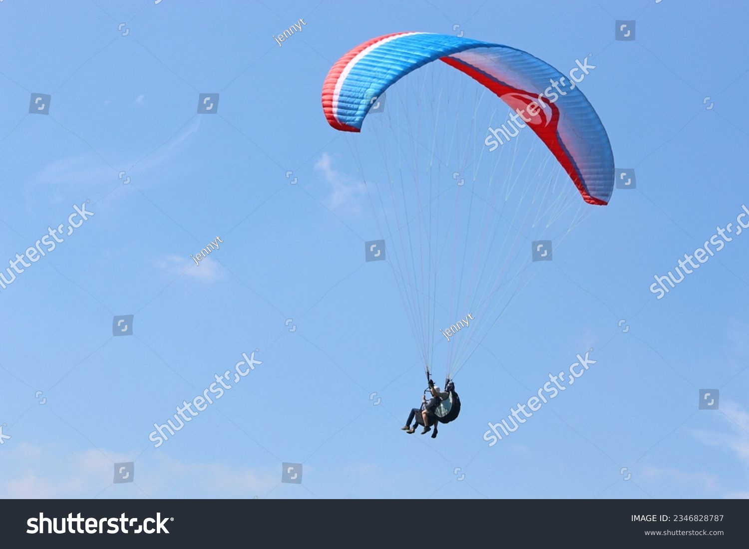 Tandem Paraglider flying in a blue sky #2346828787