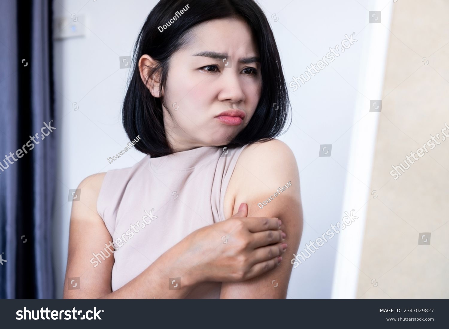 Asian woman have problem with uneven tan on arms checking on dark, sunburn and damaged skin in front of a mirror  #2347029827