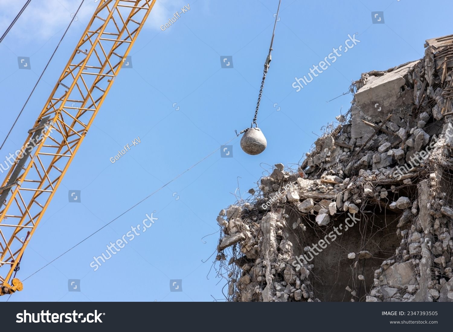 Heavy wrecking ball crane demolishing old building against blue sky in Magdeburg Germany. Building dismantling and construction waste disposal recycling service #2347393505