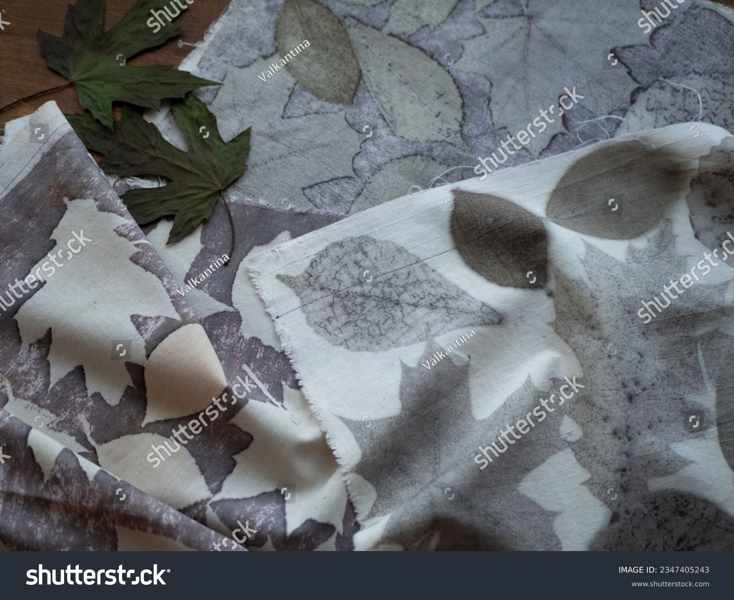 Fabric with leaves pattern and dried plants on the wooden table. Concept of eco print, botanical or natural printing #2347405243