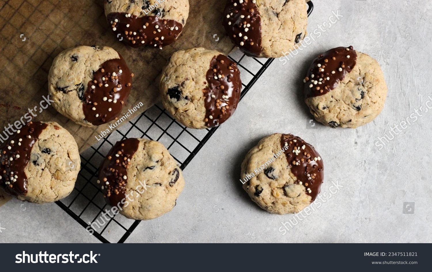 Close-up of oat cookies with raisins, dipped in chocolate and adorned with crispy bits, presented on a delicate background #2347511821