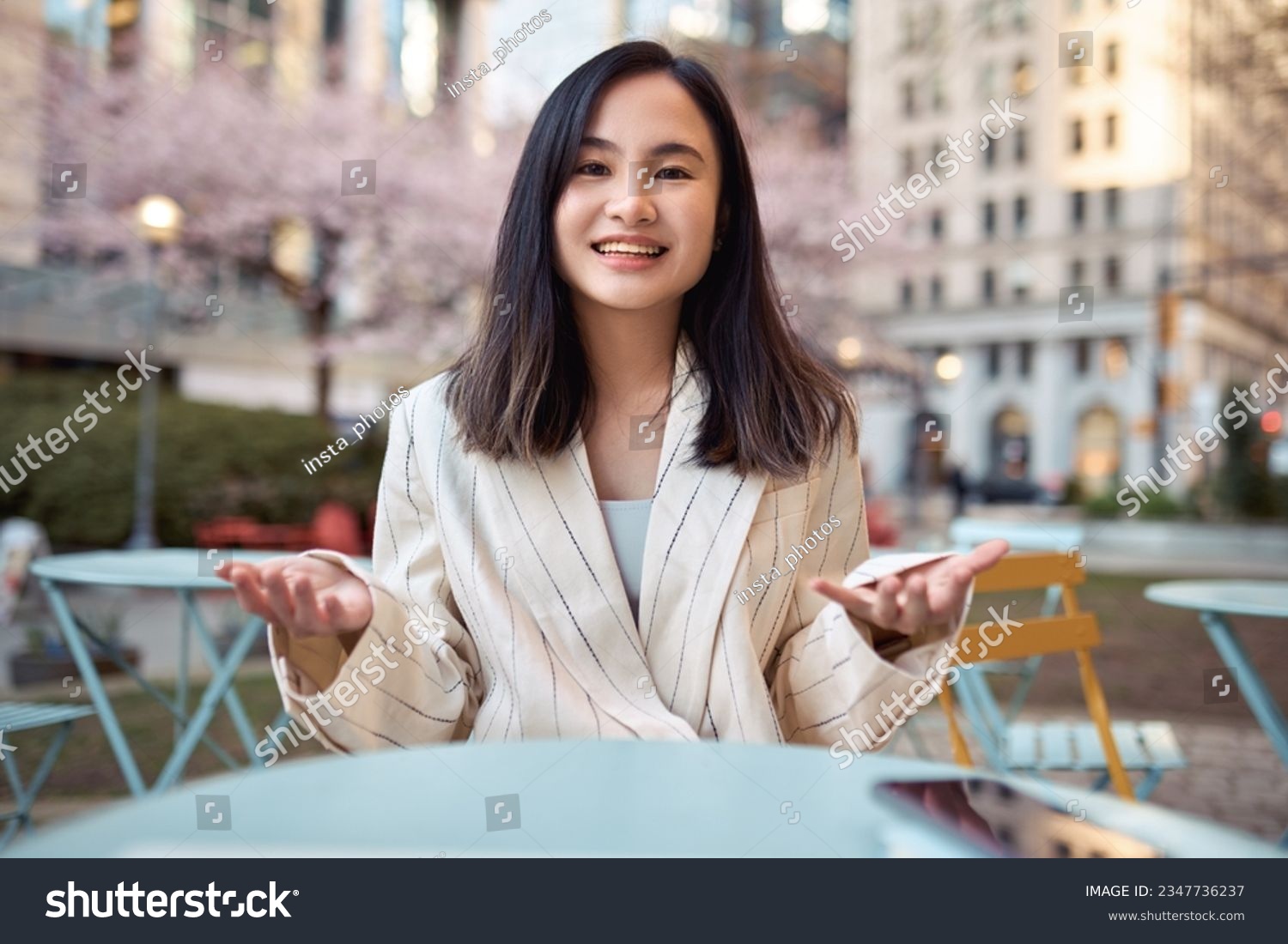 Young happy Asian business woman talking to camera outdoors having hybrid work meeting, online class, giving presentation or webinar, speaking during virtual event or shooting blog. Web cam view #2347736237