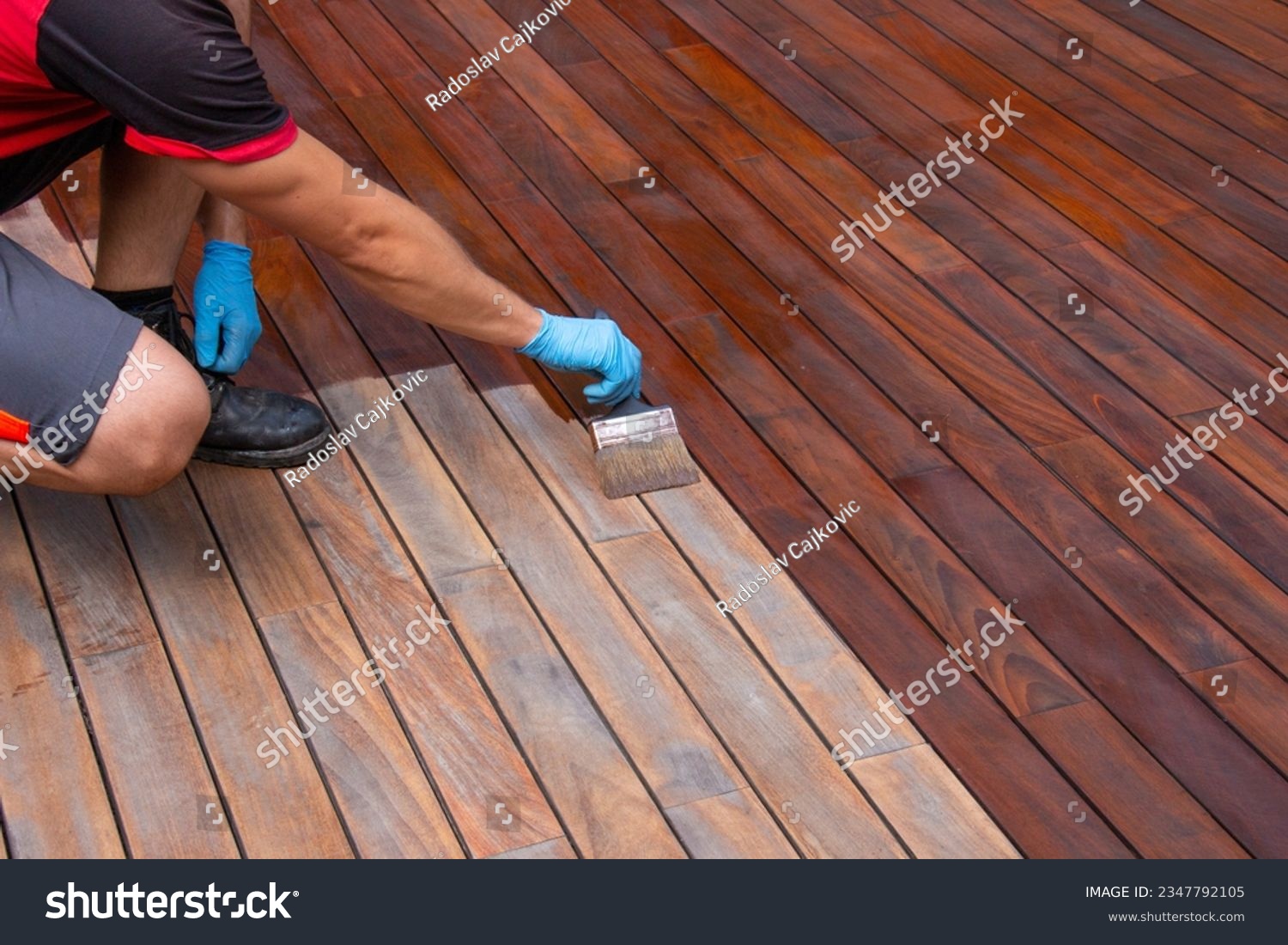 Worker applying terrace oil with a brush, wood decking renovation #2347792105