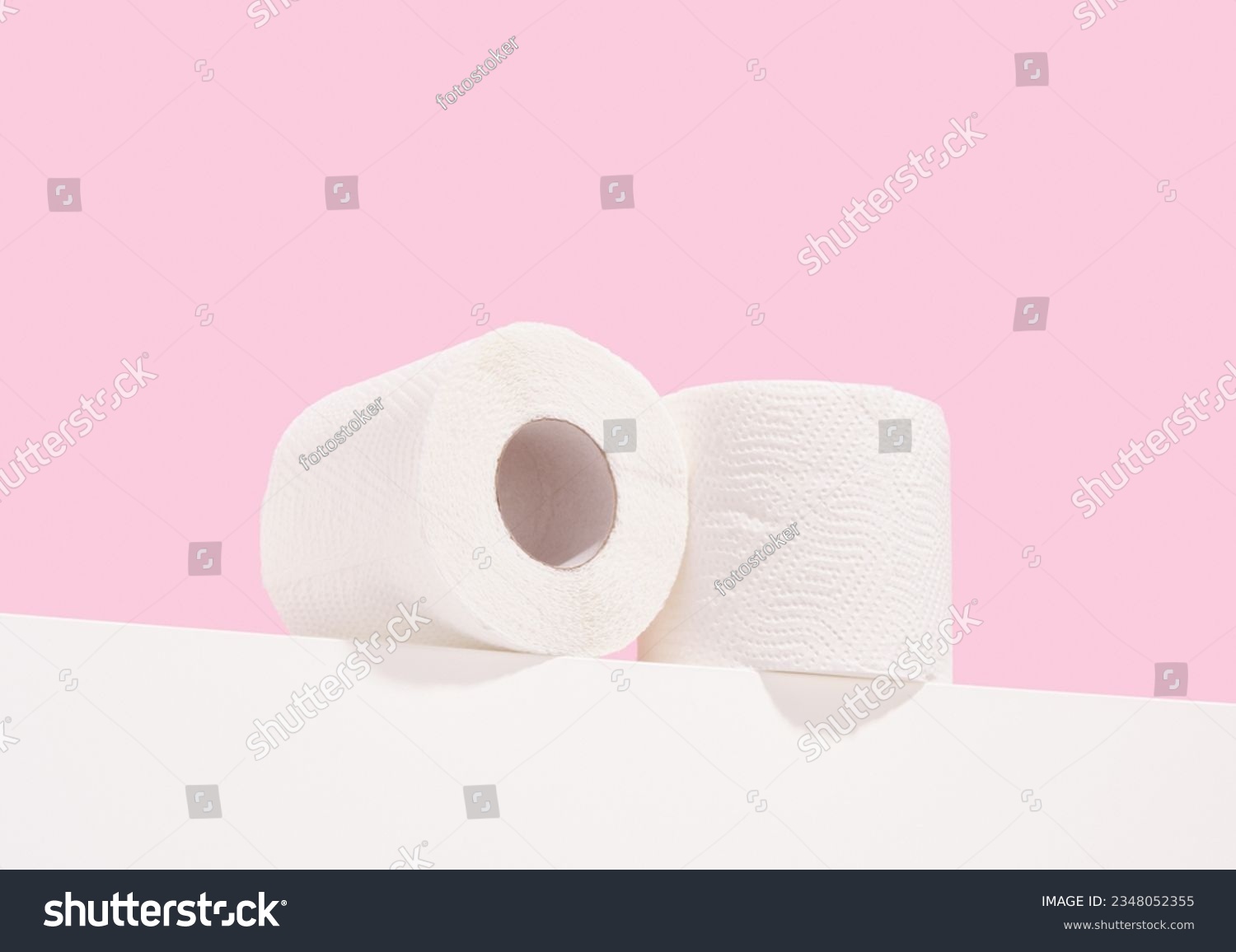 Two rolls of white toilet paper lay on the table. Personal hygiene and body care. #2348052355