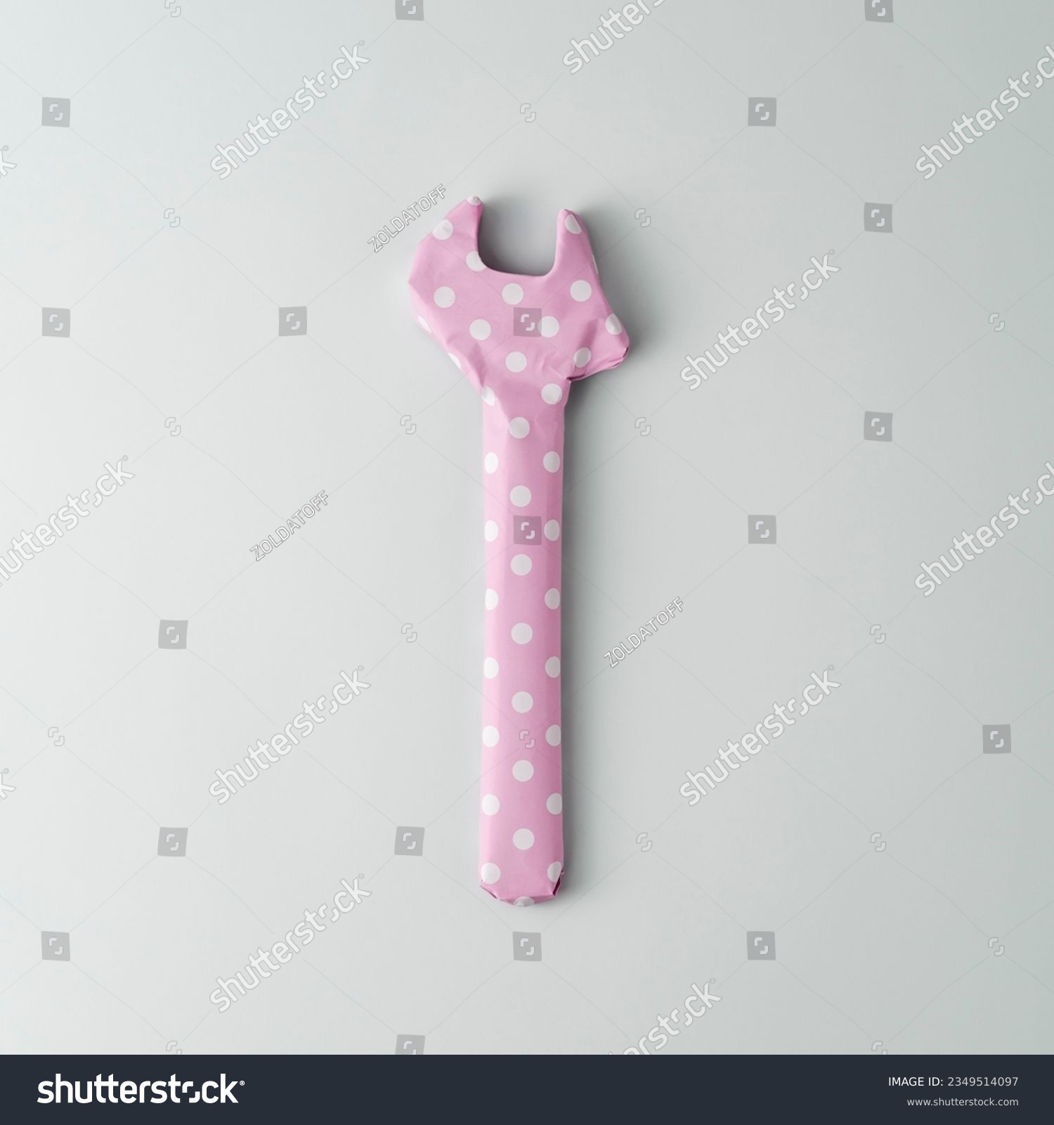 Wrench wrapped in pink polka dot gift paper on blue background. Top view.   #2349514097