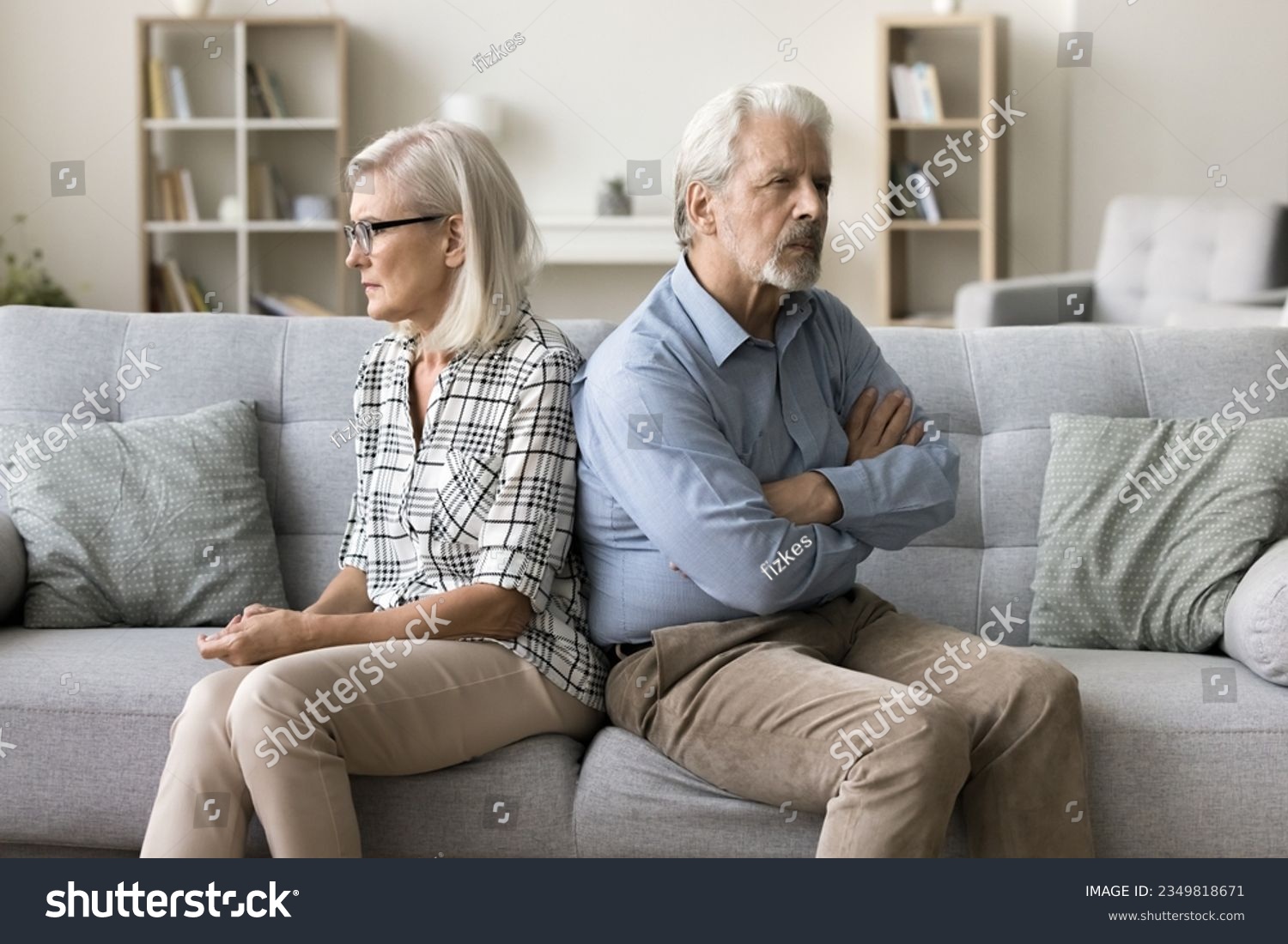 Annoyed ignoring senior couple sitting on home couch back to back, looking away, keeping silence after arguing, thinking on breakup, separation, relationship problems, conflict #2349818671