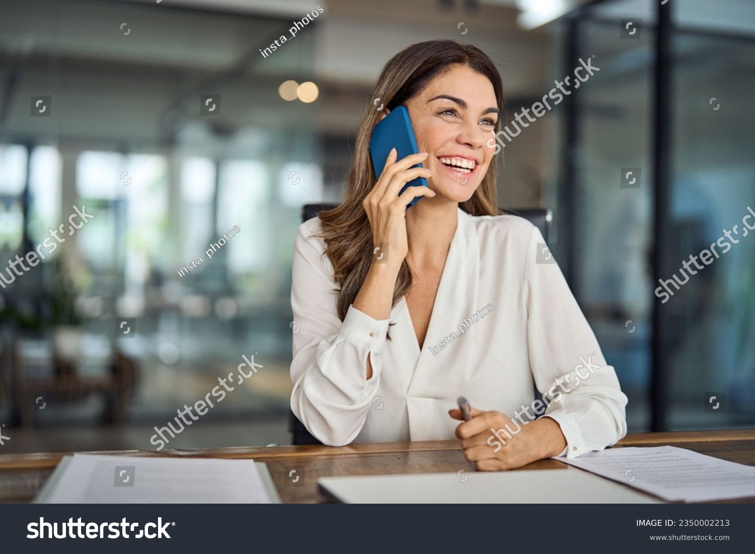Happy smiling mature mid aged business woman, cheerful 40 years old professional lady executive manager or entrepreneur talking on phone making business call on cellphone at work in office. #2350002213