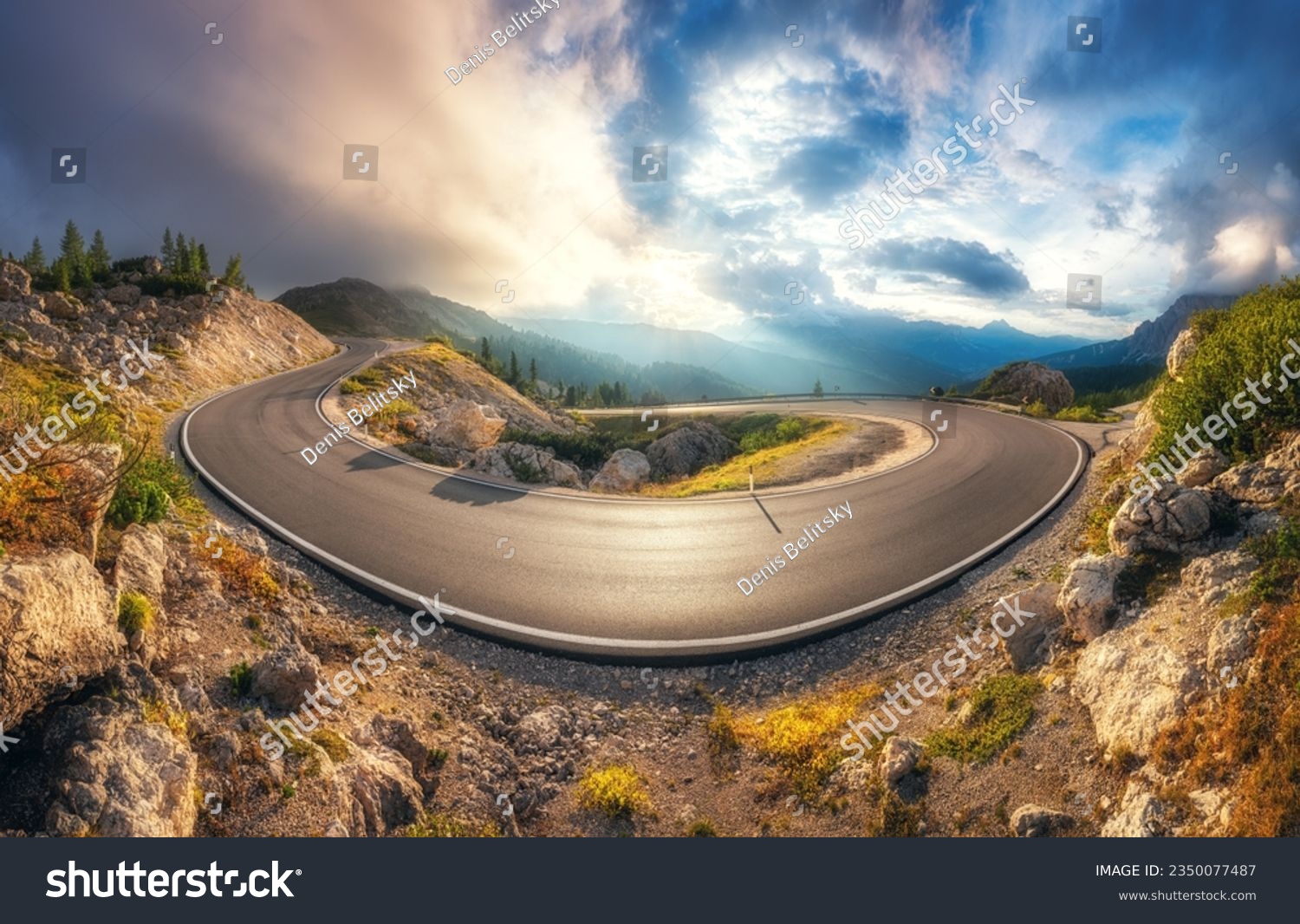 Mountain road at colorful sunset in summer. Dolomites, Italy. Beautiful curved roadway, rocks, stones, blue sky with clouds. Landscape with empty highway through the mountain pass in spring. Panorama #2350077487