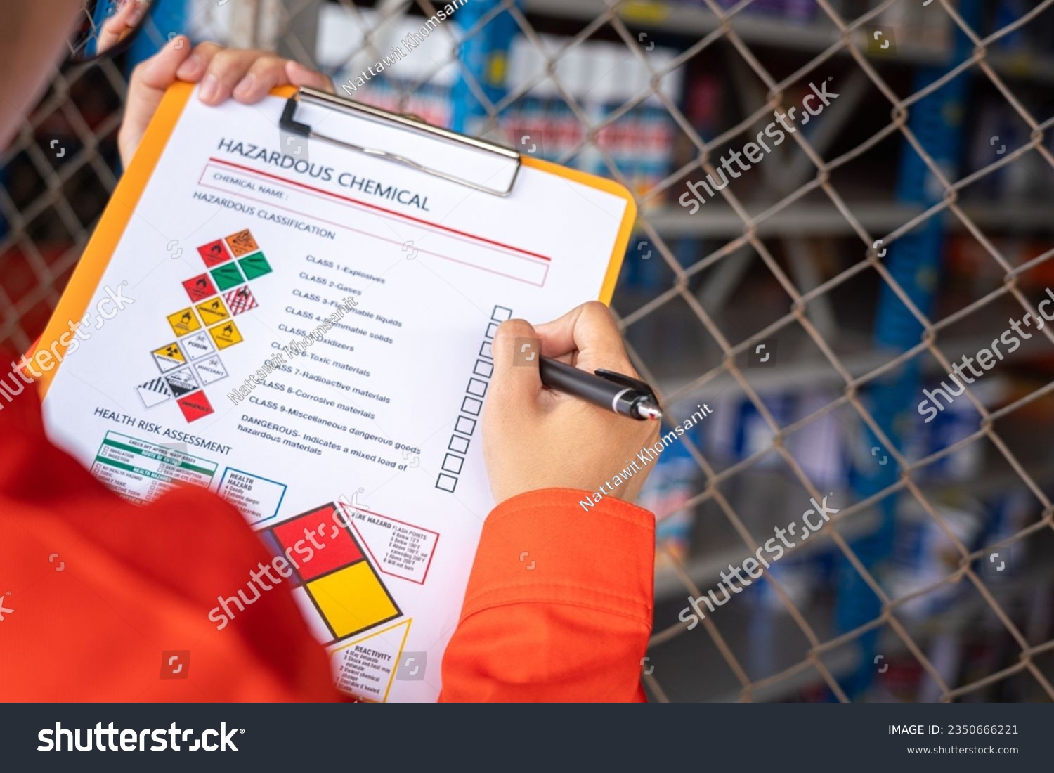 A worker is checking on the hazardous chemical material information form with background of chemical storage area at the factory place. Industrial safety working action. Selective focus. #2350666221