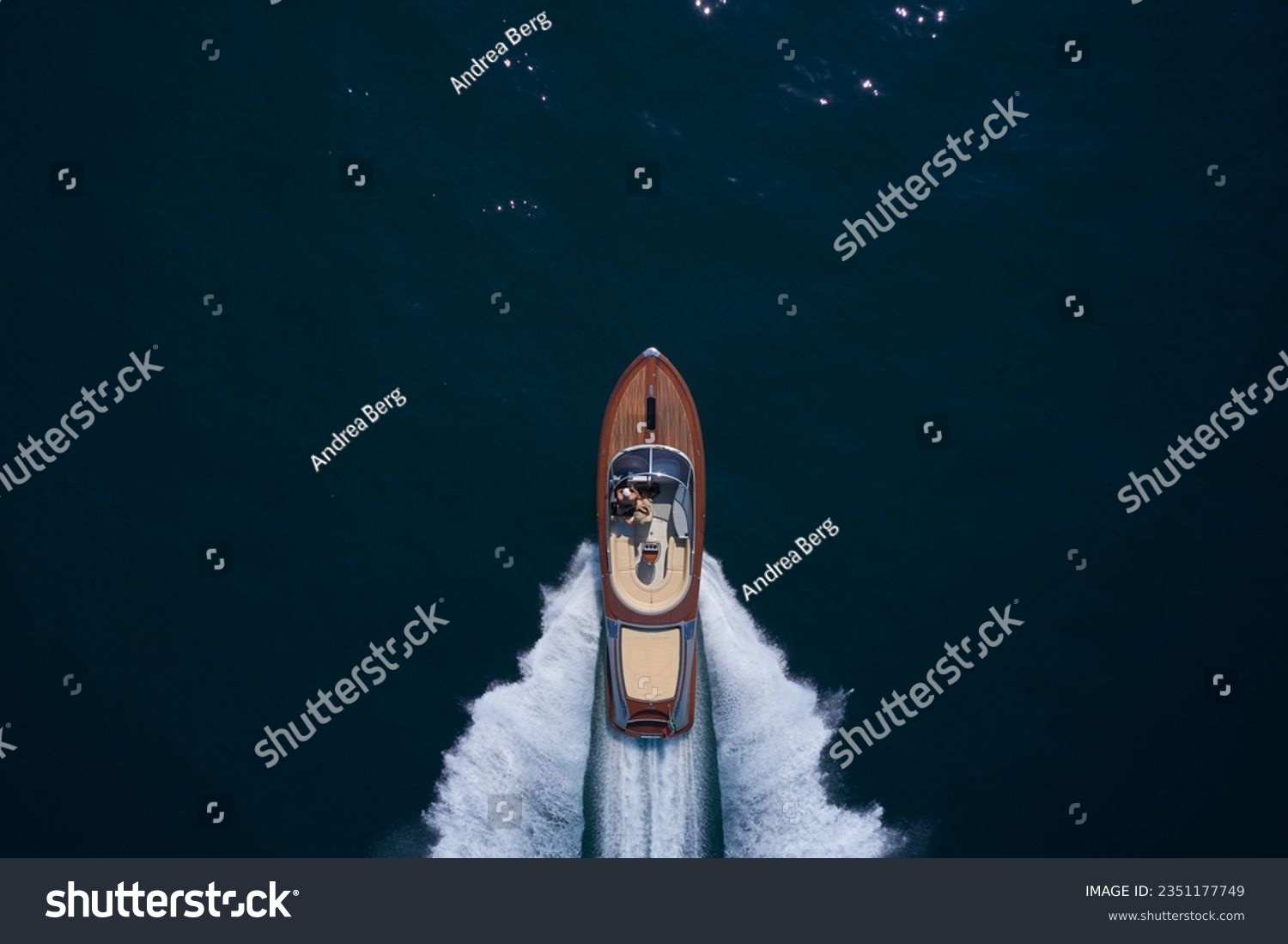 Top view of a wooden powerful motor boat. Luxurious wooden boat fast movement on dark water.Man and woman in luxury expensive wooden speedboat fast moving on dark water top view. #2351177749