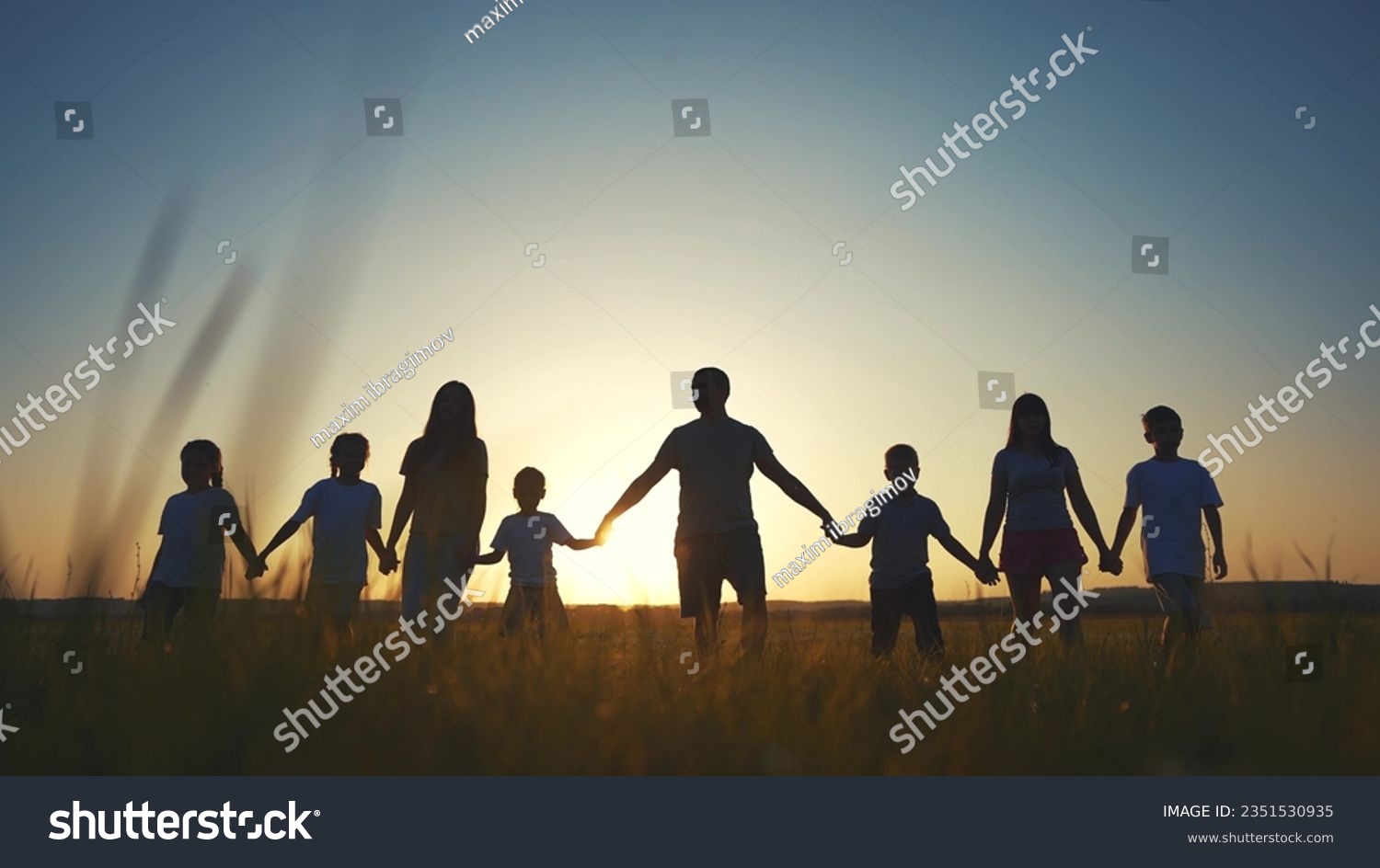 large family walks across field holding hands. happy family childhood dream concept. family walks across the field on the grass lifestyle at sunset and hold each other's hands dark silhouettes #2351530935