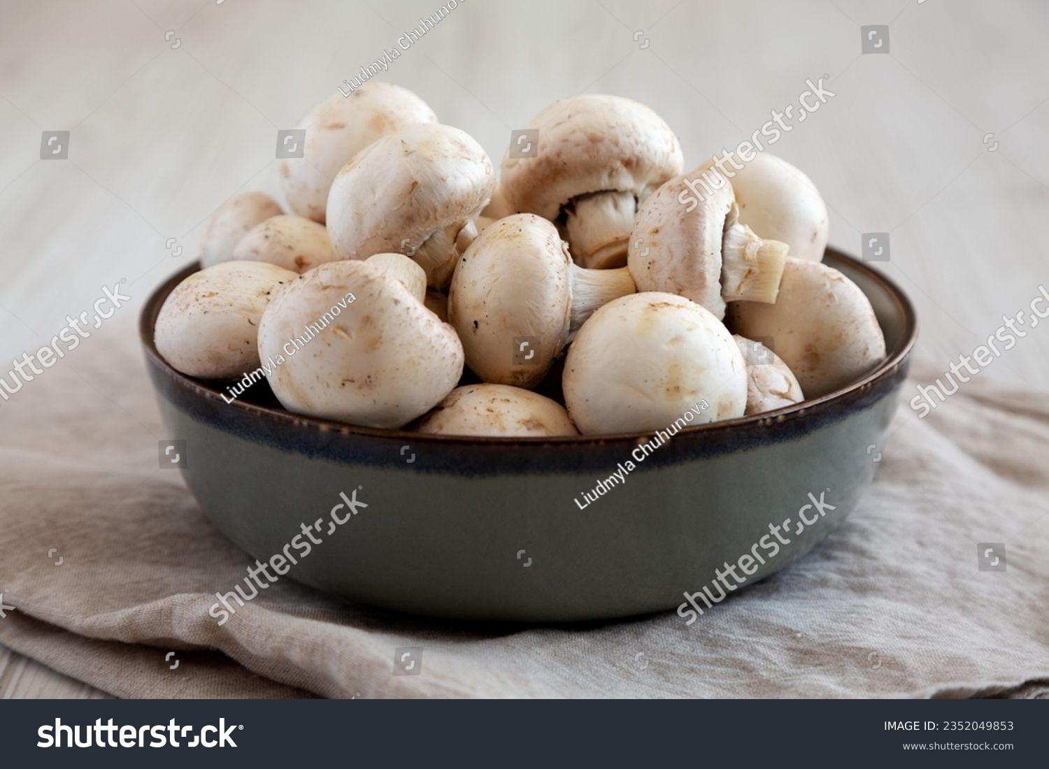 Raw White Champignon Mushrooms in a Bowl on a white wooden background, side view. Close-up. #2352049853