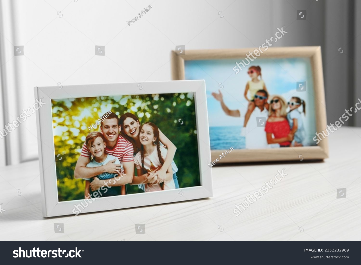 Framed family photos on white wooden table indoors. Space for text #2352232969