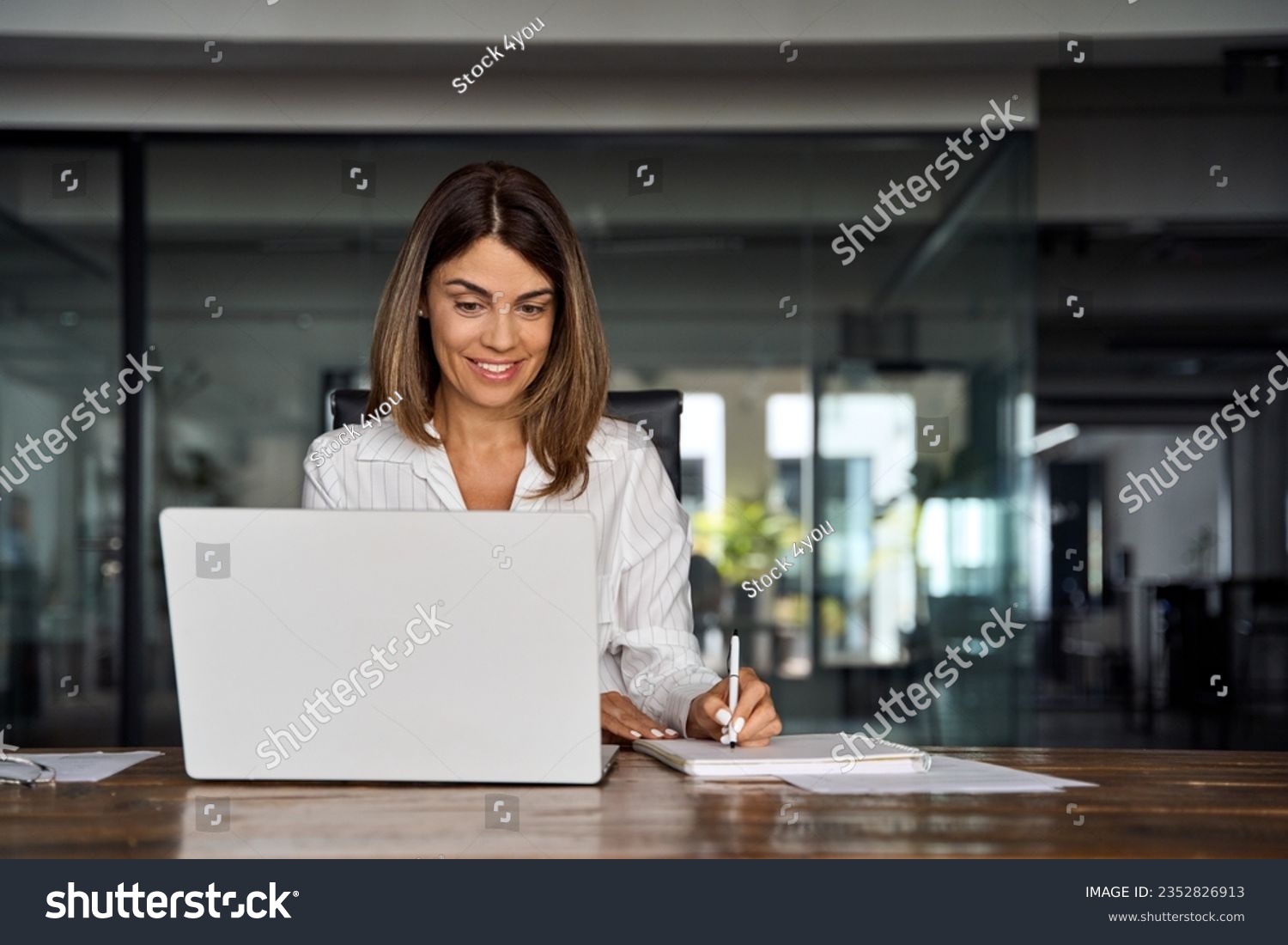 Middle-age Hispanic woman using laptop computer for business studying, watch online virtual webinar training meeting,video call. Focused mature 40s years Latin businesswoman work in office, copy space #2352826913