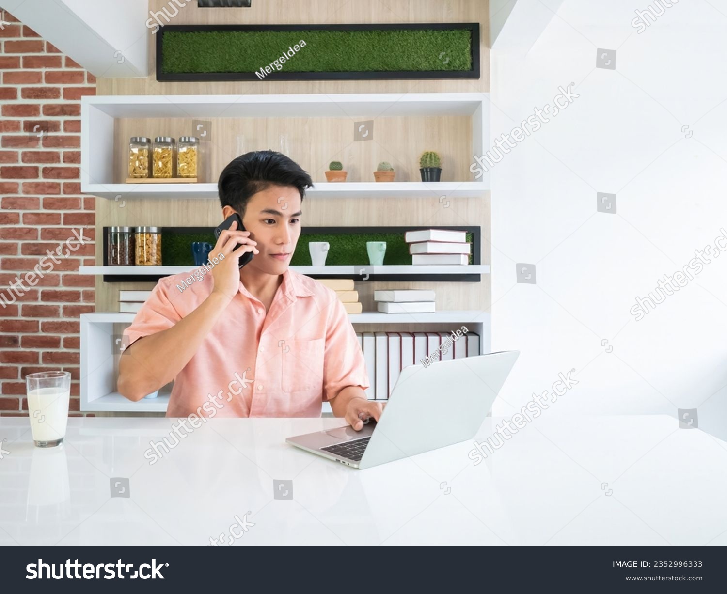 Asian traveller man confirm booking with airline call center by smartphone and check flight route and date by laptop together on kitchen home multitasking in the morning #2352996333