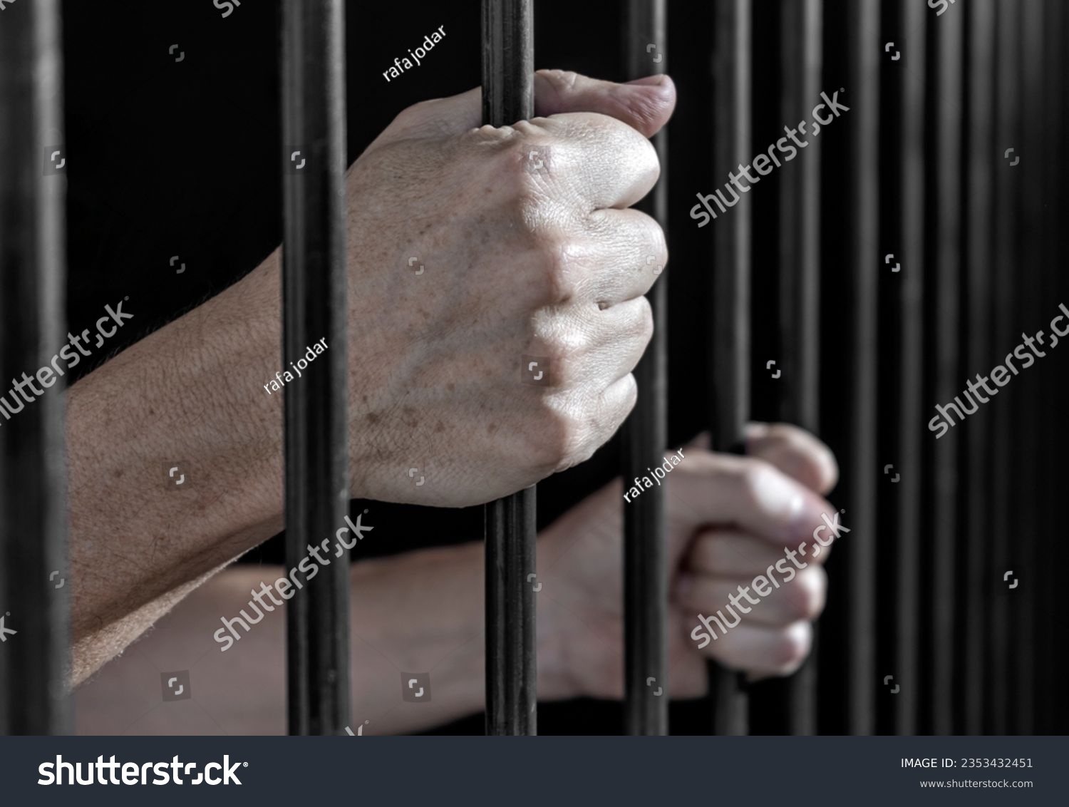Prisoner's hands gripping the bars of a cell in jail or prison serving sentence. #2353432451