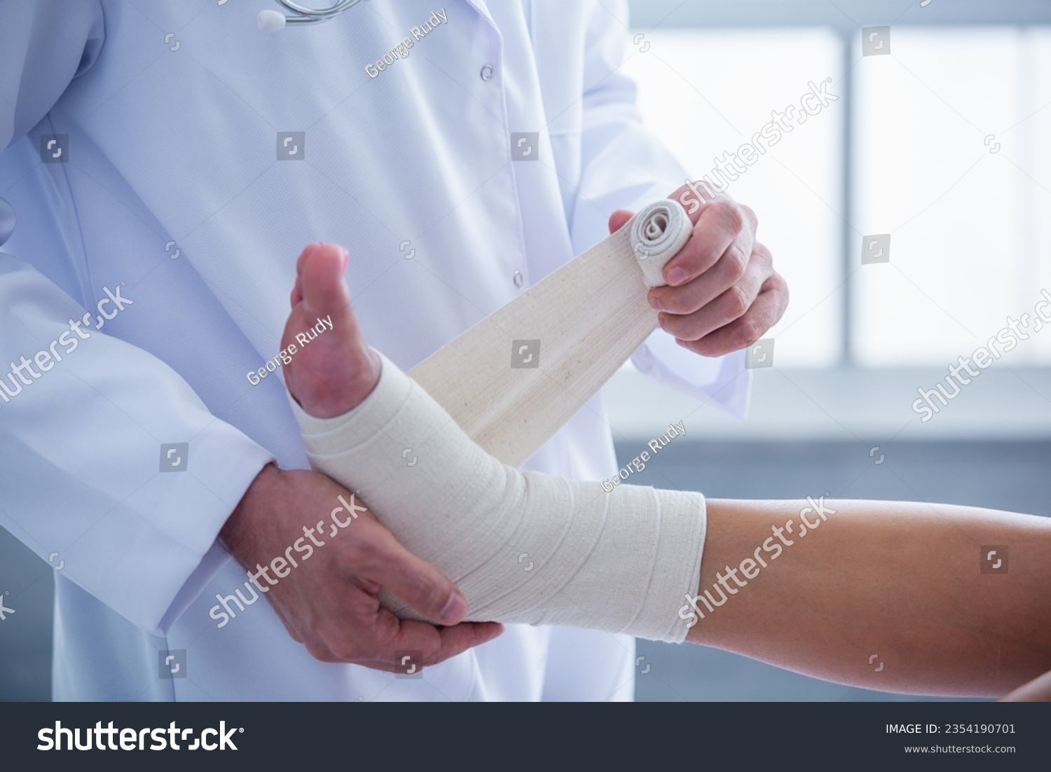 Cropped image of handsome doctor bandaging woman's injured leg while working in his office #2354190701