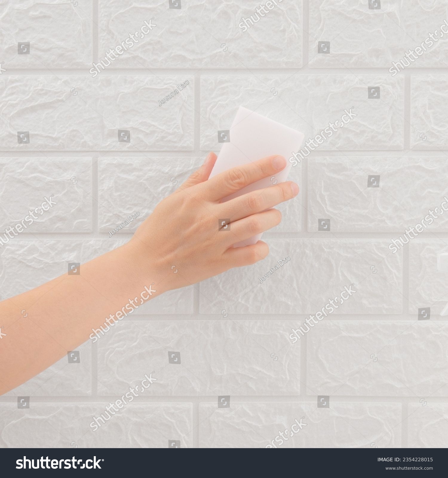 White sponge in hand cleaning wall tiles. Cleaning concept and household product. Melamine. #2354228015